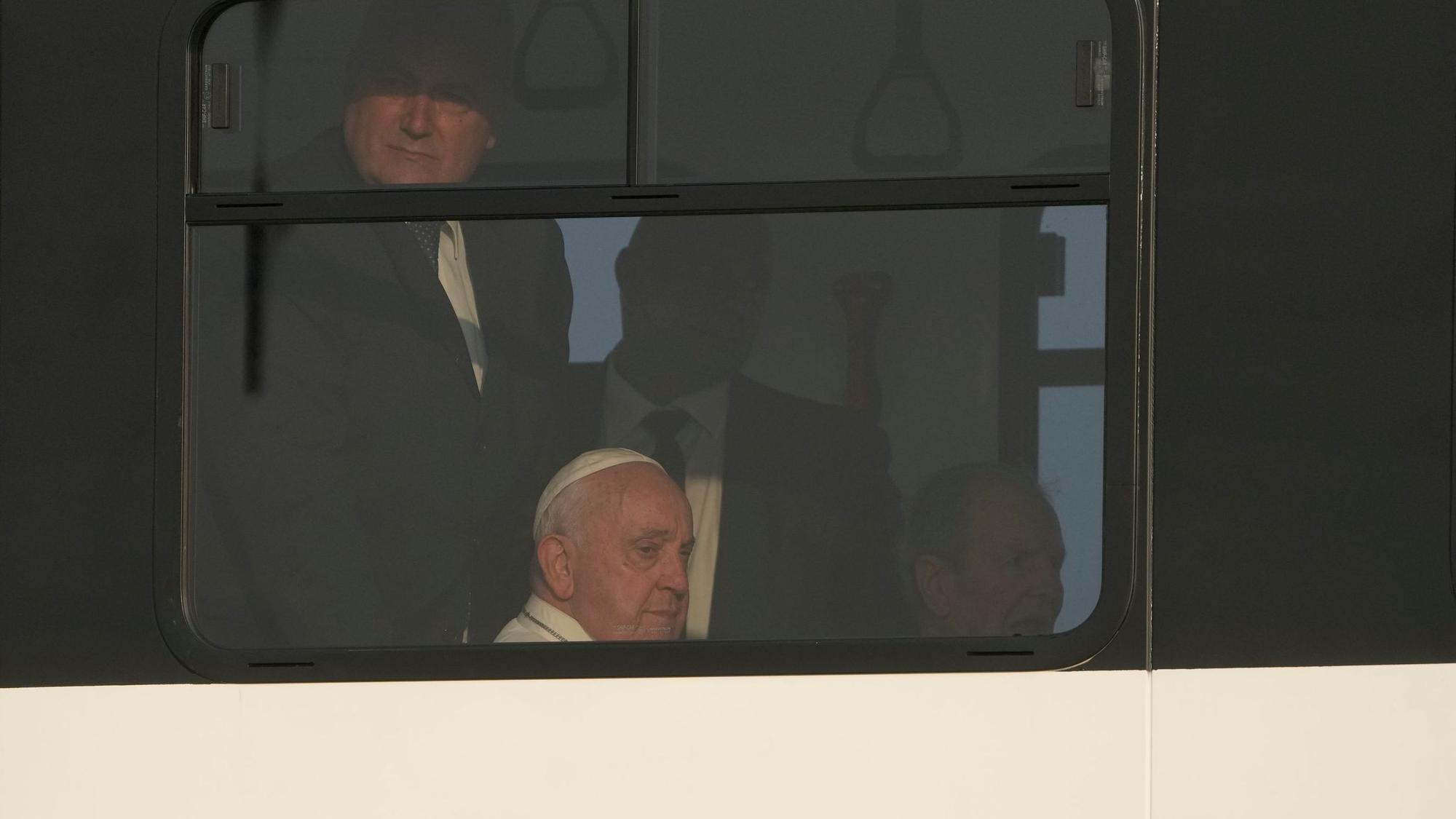 Papst Franziskus (M) sitzt in einem Shuttlebus zwischen seinen ständigern Begleitern, den Sicherheitsleuten.
