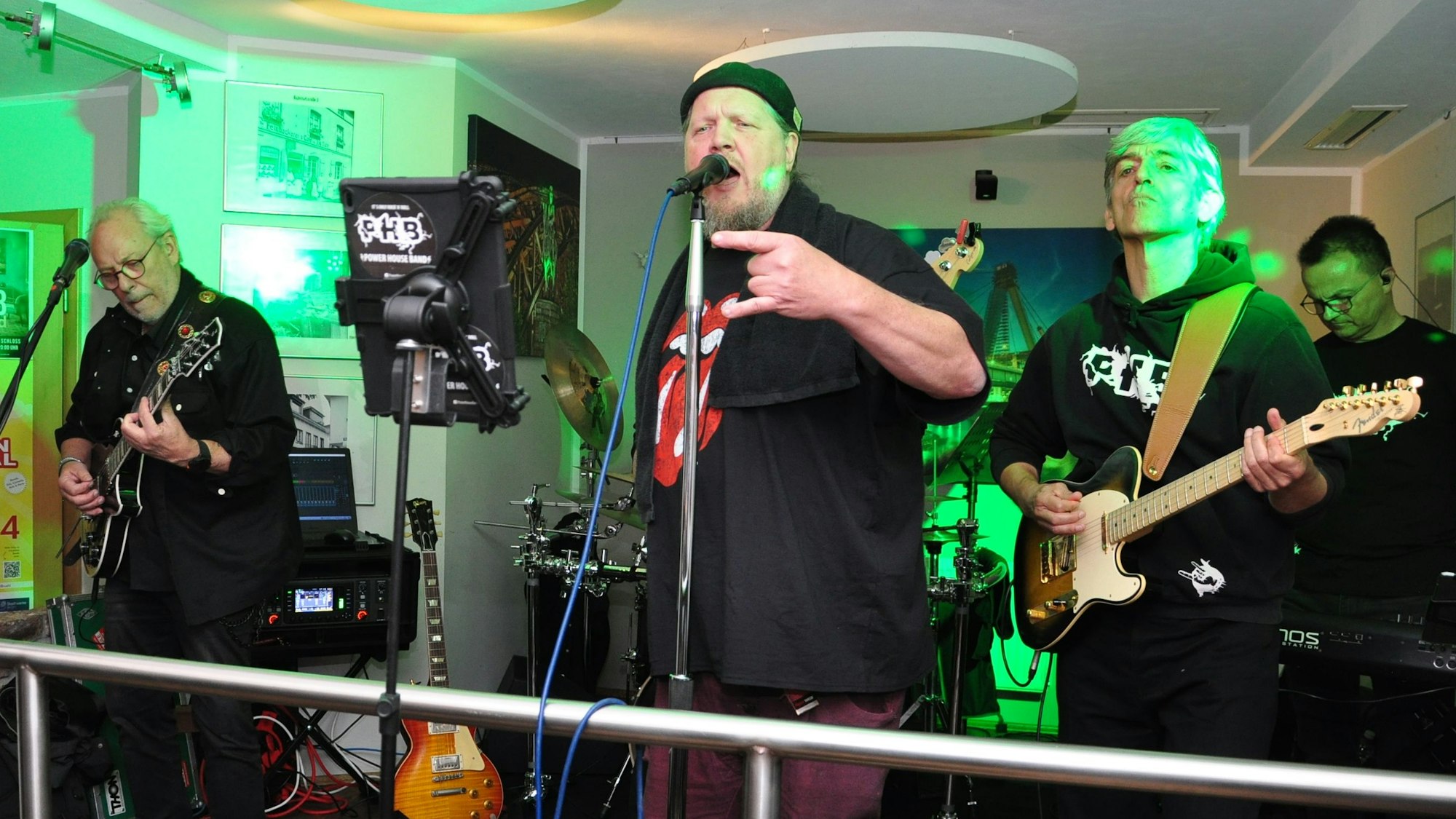 Ein Sänger und zwei Gitarristen treten in einer Kneipe auf.