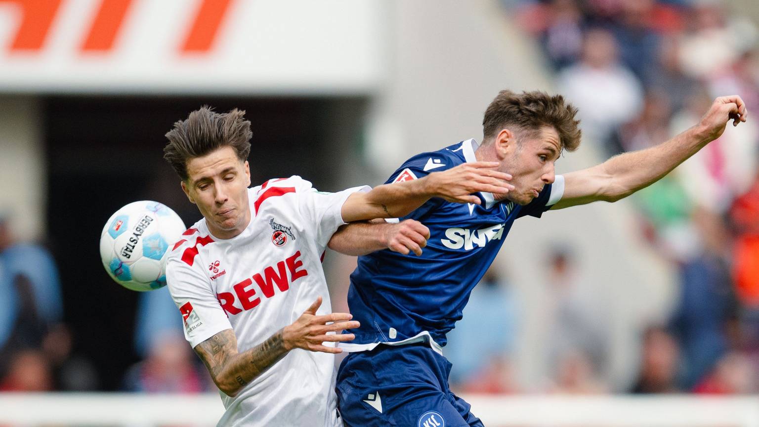 Kölns Denis Huseinbasic (l) und Karlsruhes Leon Jensen kämpfen um den Ball.