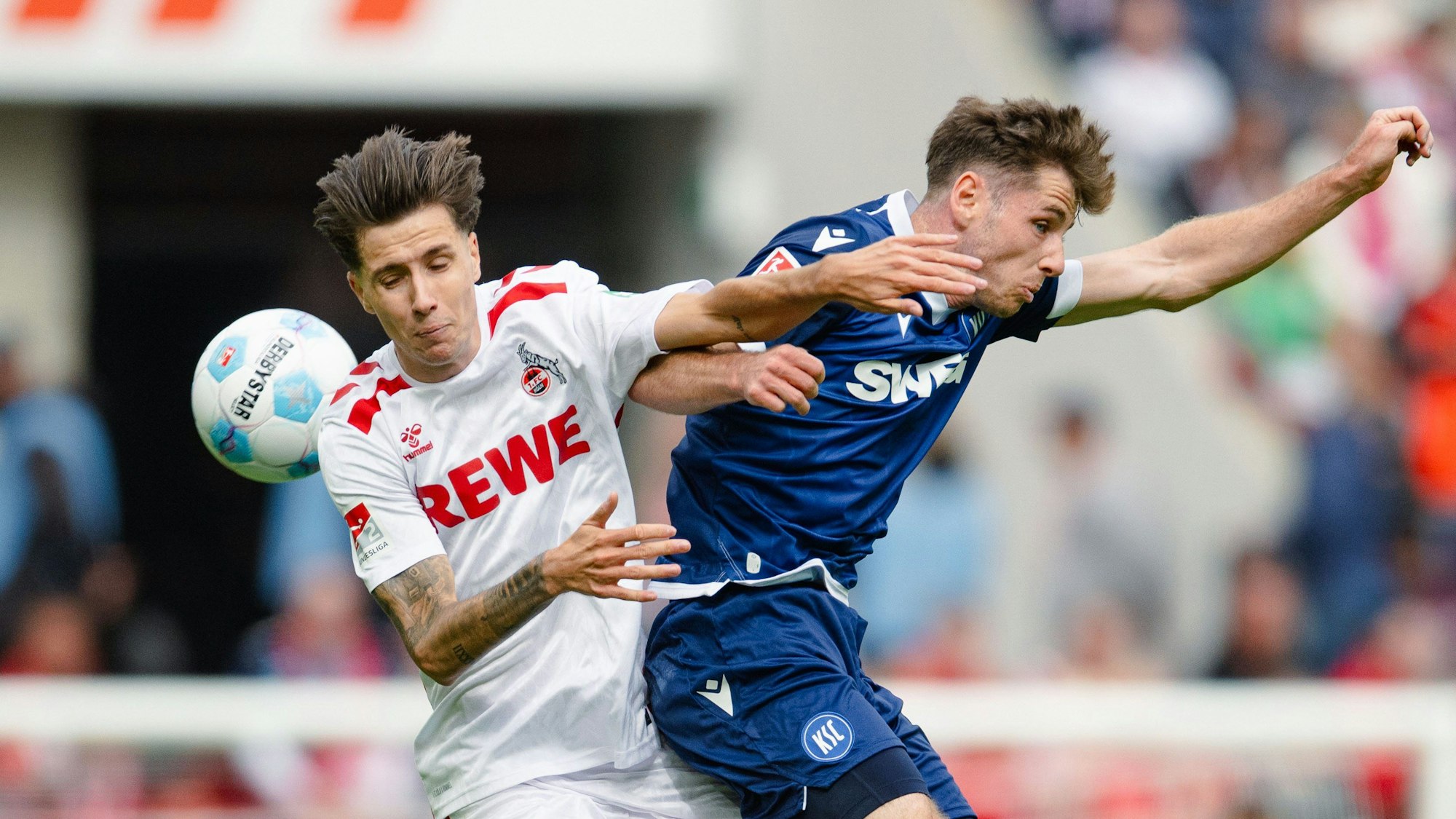 Kölns Denis Huseinbasic (l) und Karlsruhes Leon Jensen kämpfen um den Ball.