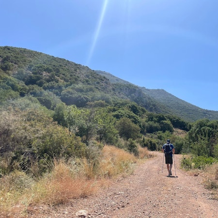 Ein Tourist geht bei wolkenlosem Himmel auf einer griechischen Insel Wandern (Symbolfoto).