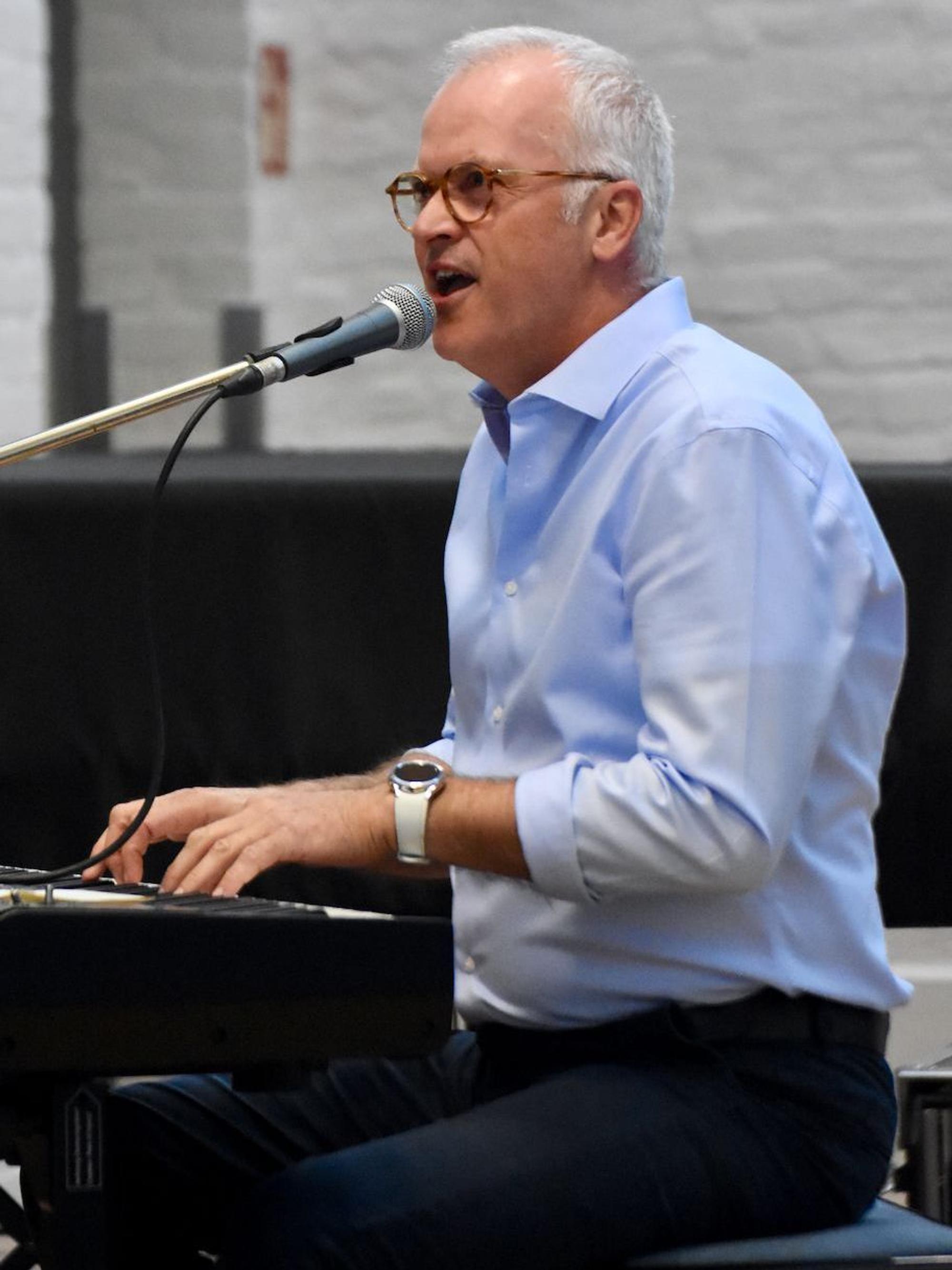 Eingrauhgaariger Mann sitzt im Kurtheater Hennef am Klavier.