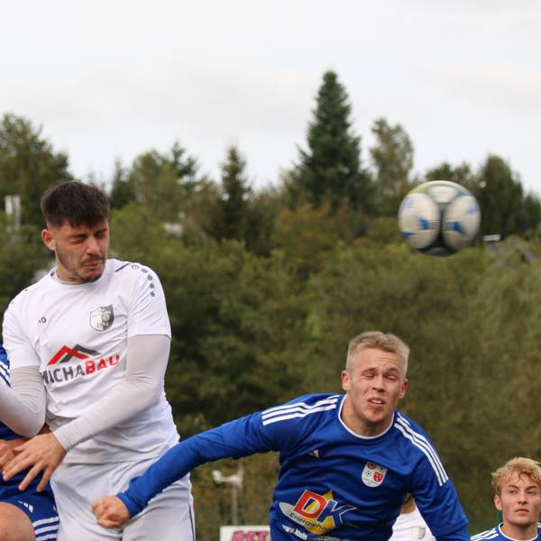 Drei Fußballer springen zum Kopfball hoch. Alle drei haben die Augen geschlossen.