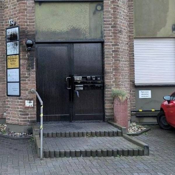 Der Eingangsbereich zu einem Mehrparteienhaus ist zu sehen. Büroschilder an der Türe sind übermalt.
