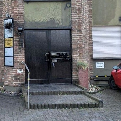 Der Eingangsbereich zu einem Mehrparteienhaus ist zu sehen. Büroschilder an der Türe sind übermalt.