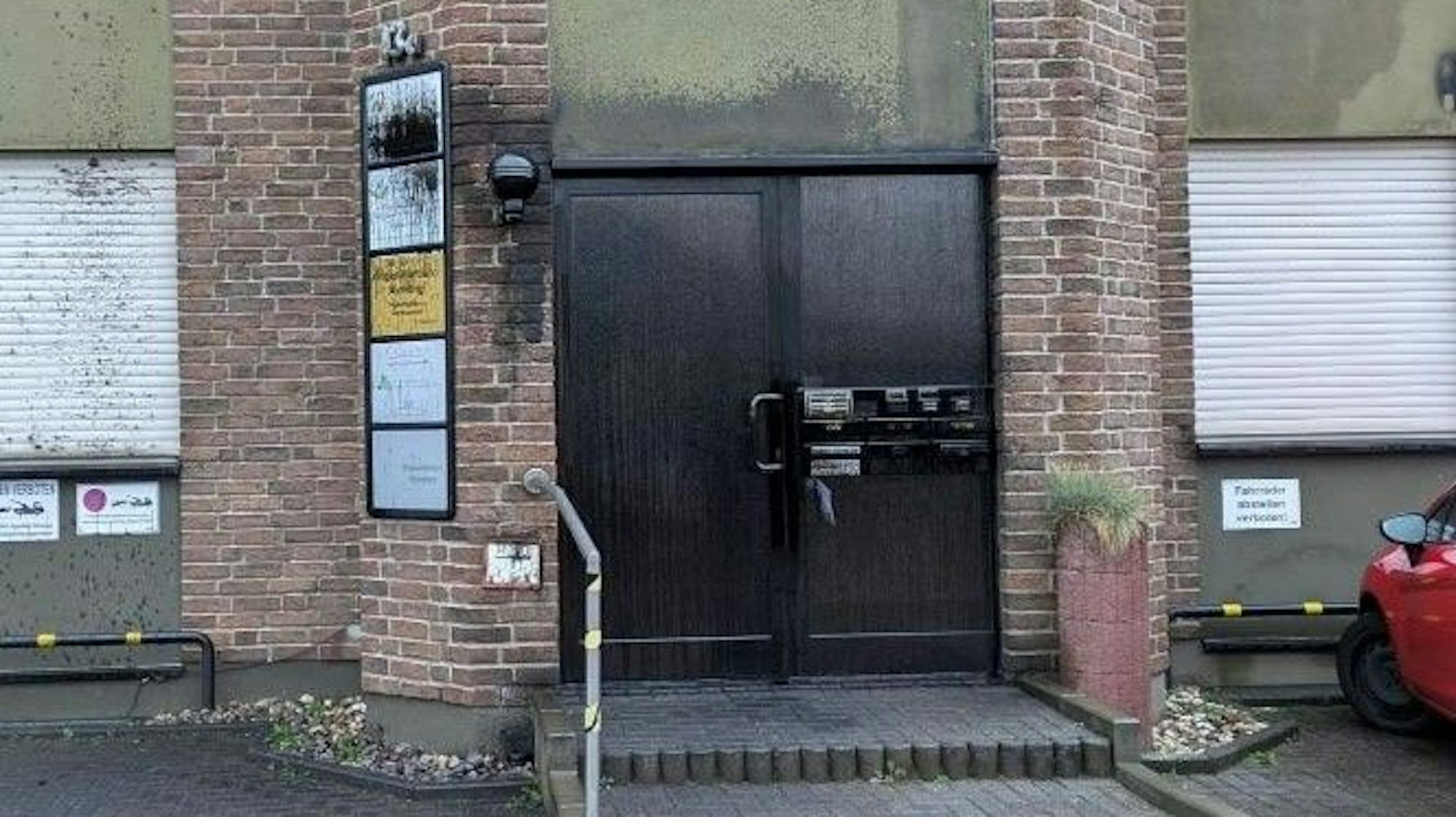 Der Eingangsbereich zu einem Mehrparteienhaus ist zu sehen. Büroschilder an der Türe sind übermalt.