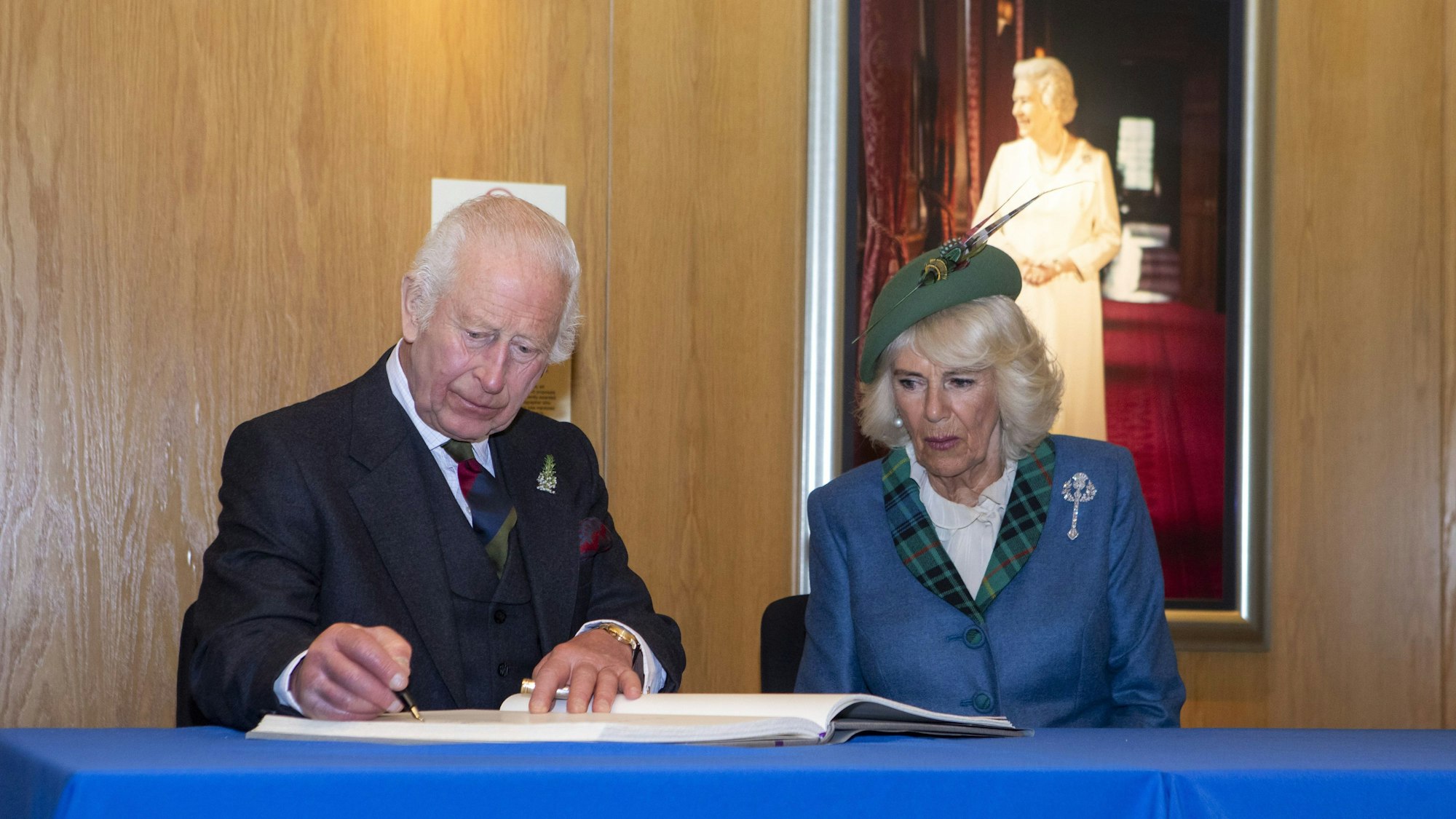 König Charles III. und Königin Camilla tragen sich nach einer Veranstaltung im schottischen Parlament in Holyrood, Edinburgh, anlässlich des 25-jährigen Bestehens des schottischen Parlaments in das Gästebuch ein.