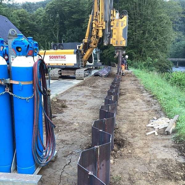 Ein Bagger und ein Bauarbeiter am Flussufer