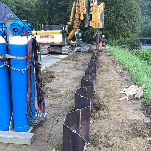 Ein Bagger und ein Bauarbeiter am Flussufer