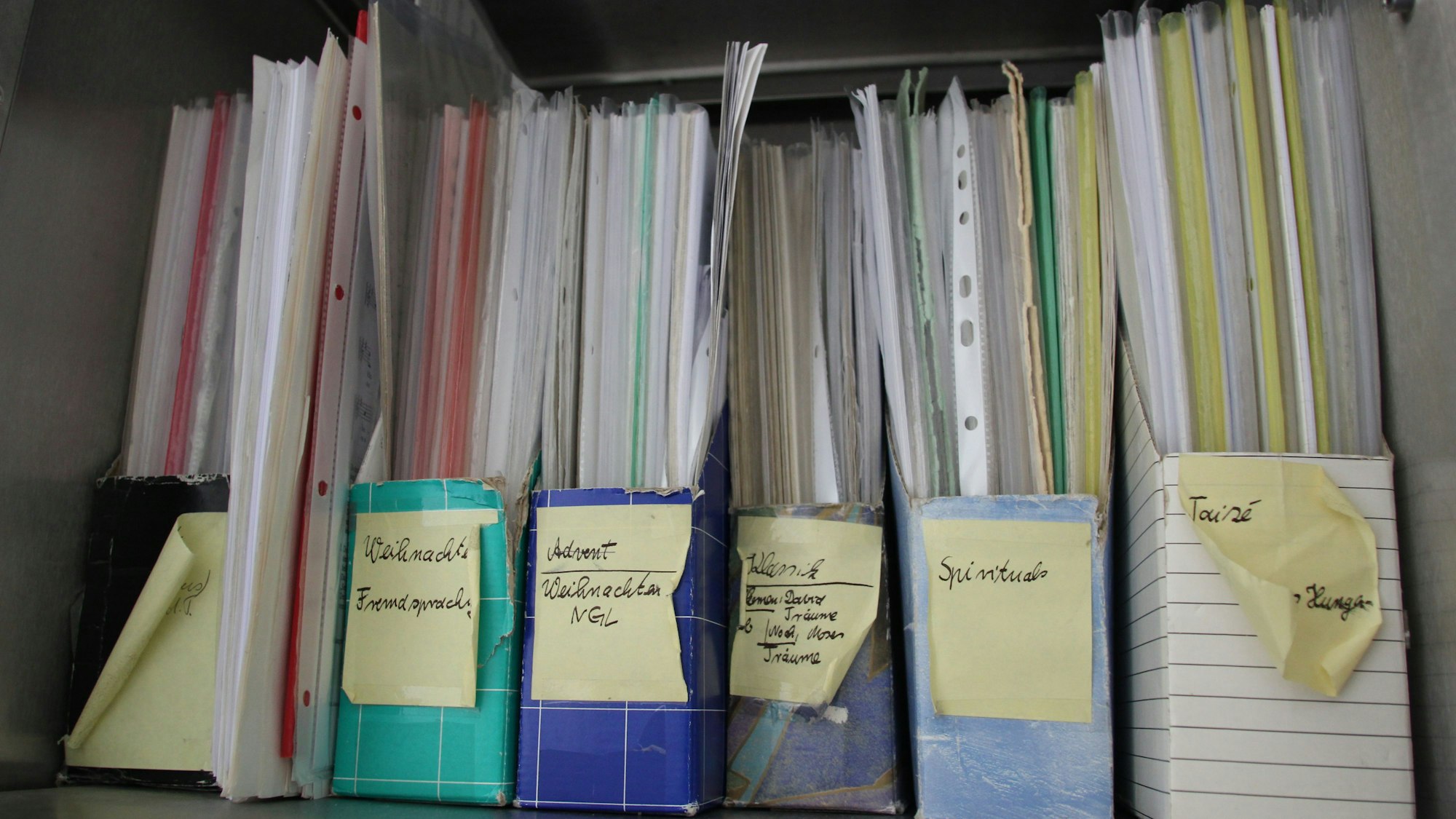 Ordner mit beschrifteten Rücken sind zu sehen, darin viele Blätter und Schutzhüllen.