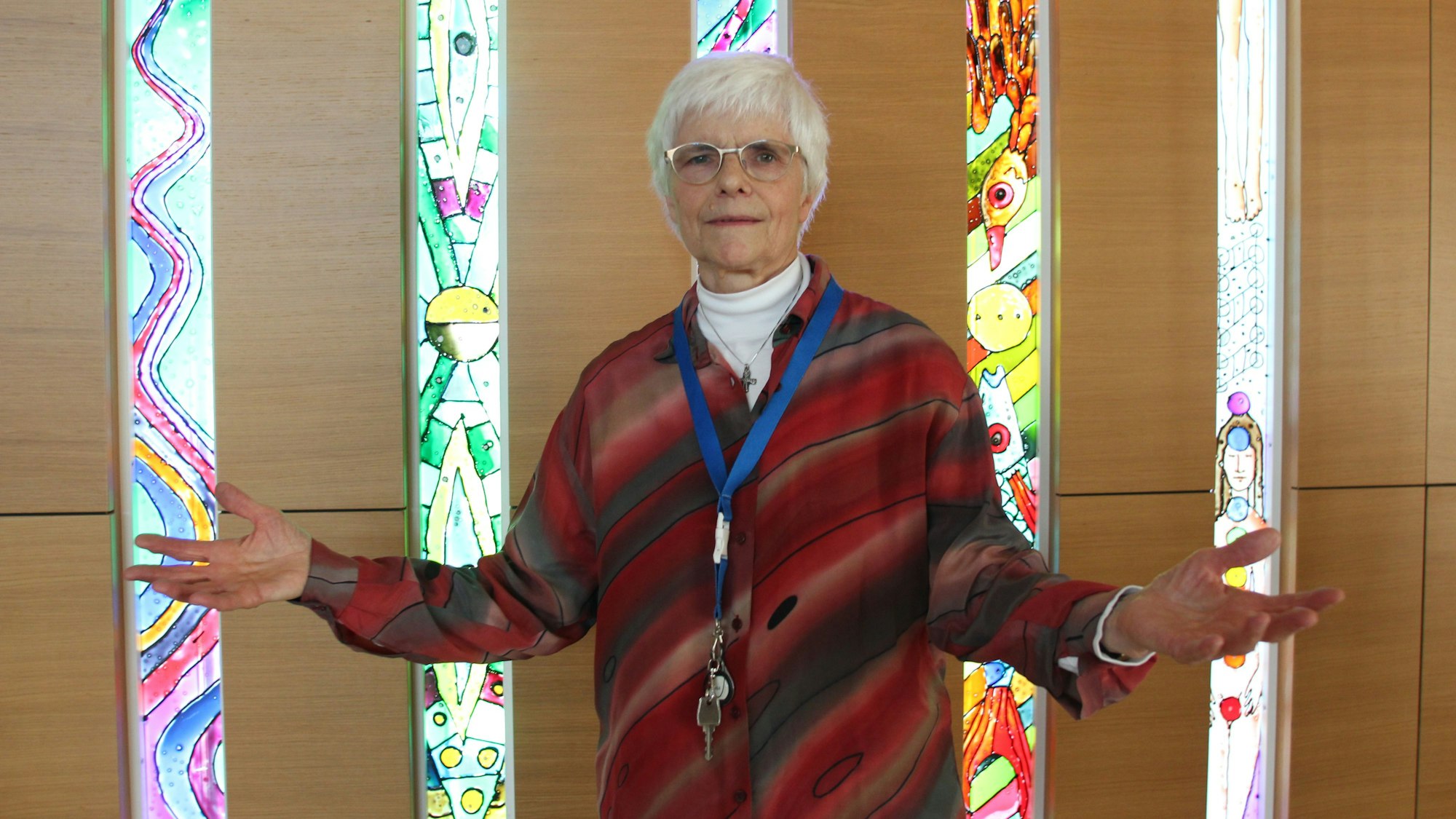 Lioba Lichtschlag ist vor bunten Glasfenstern eines Andachtsraums zu sehen.