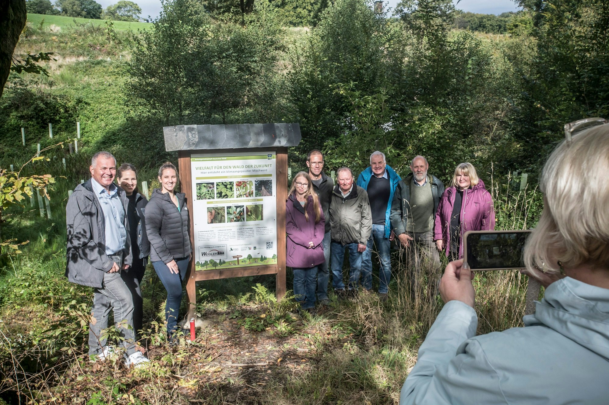 Gruppenbild: Eine Tafel informiert über die Pflanzung.