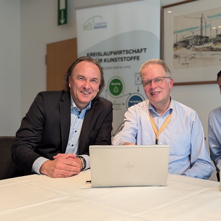 Das Foto zeigt drei Männer im Feierabendhaus hinter einem aufgeklappten Laptop.