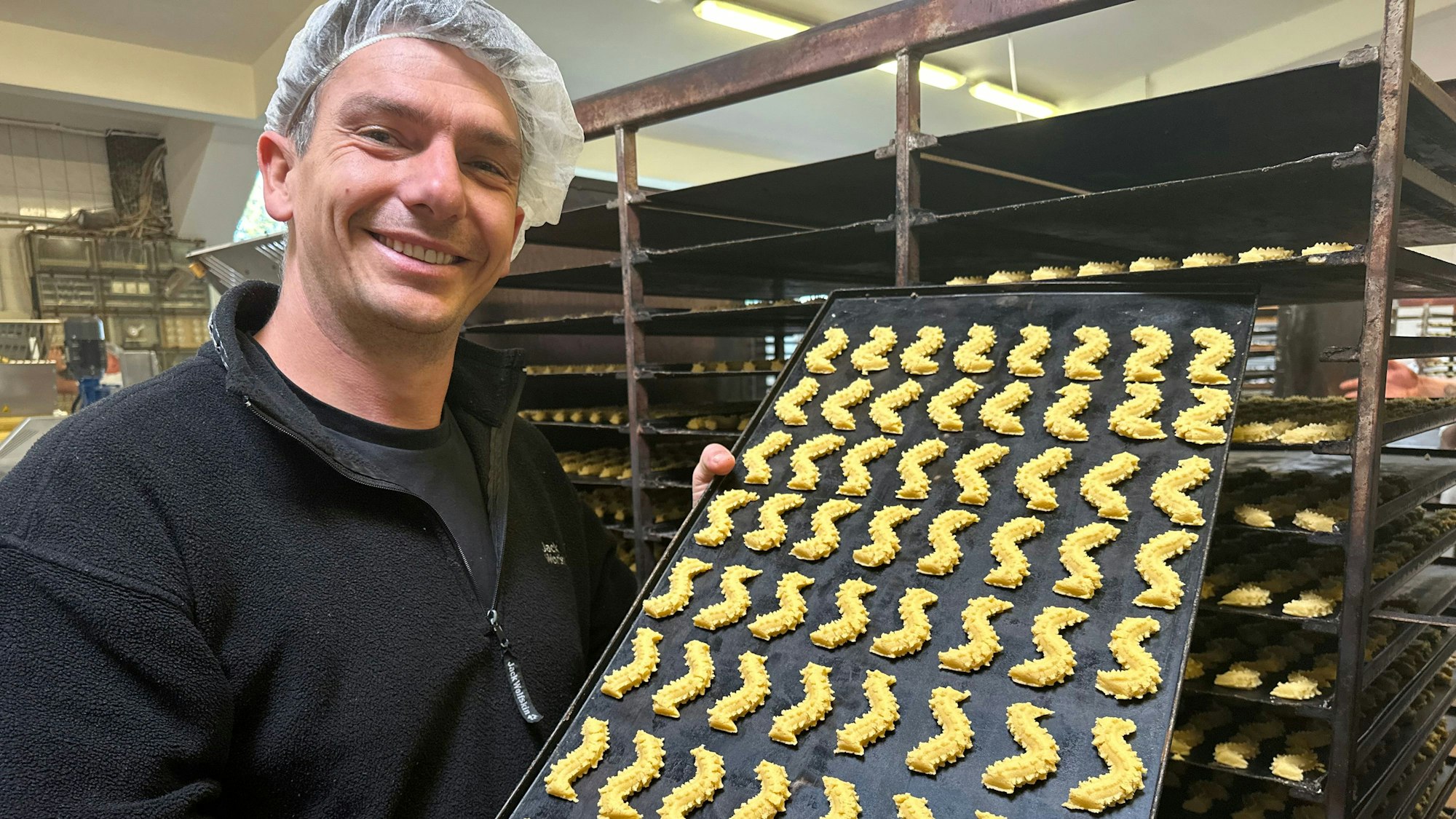 Firmenchef Cliff Lassche mit einem Blech von Plätzchen, die gleich in den Ofen kommen.