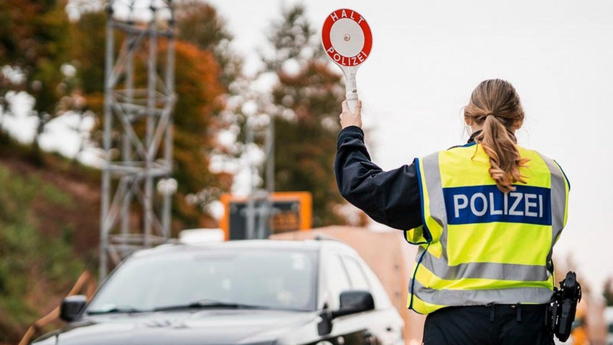 Eine Beamtin der Bundespolizei hält eine Polizeikelle in die Höhe.