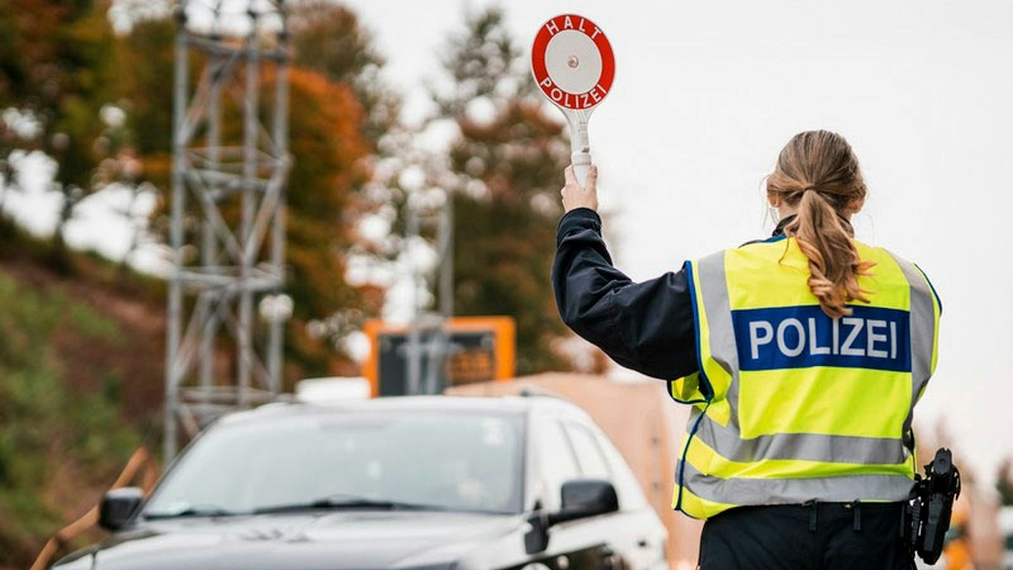 Eine Beamtin der Bundespolizei hält eine Polizeikelle in die Höhe.