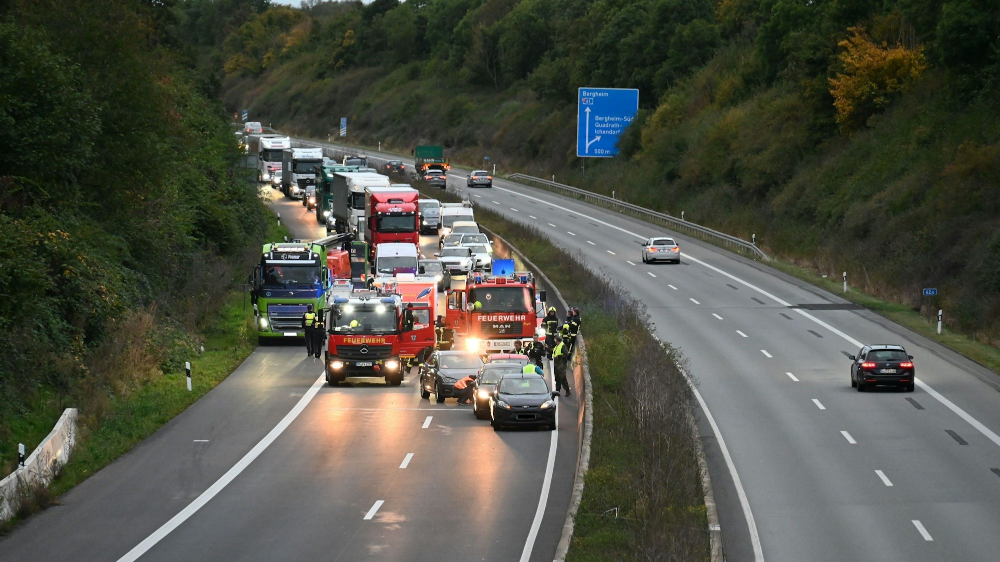 Pkw, Lkw und Feuerwehrwagen stehen nach einem Unfall auf der A61 im Stau.