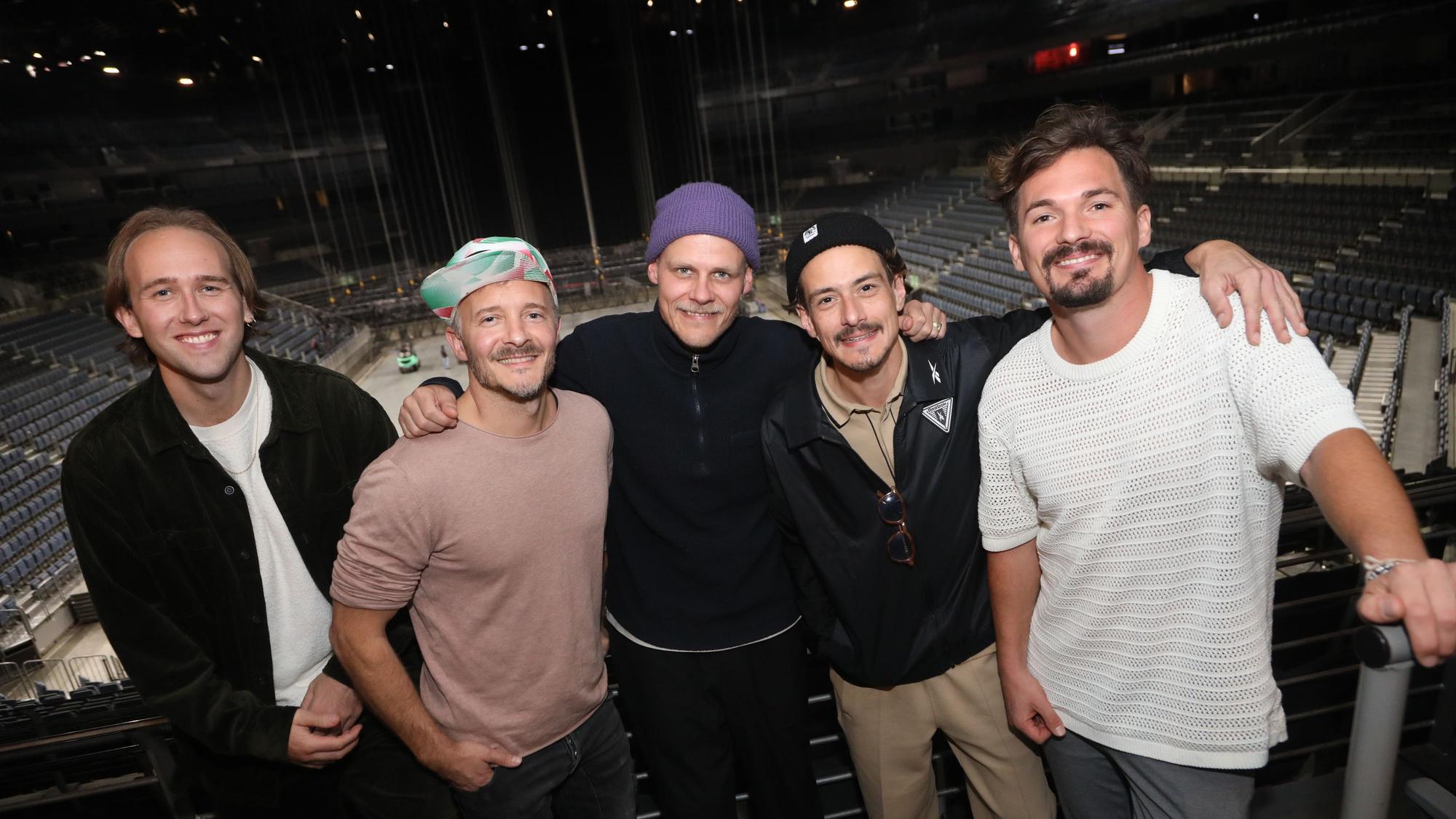 Die Musikband Cat Ballou vor den Rängen der Lanxess-Arena, die Mitglieder schauen glücklich in die Kamera.