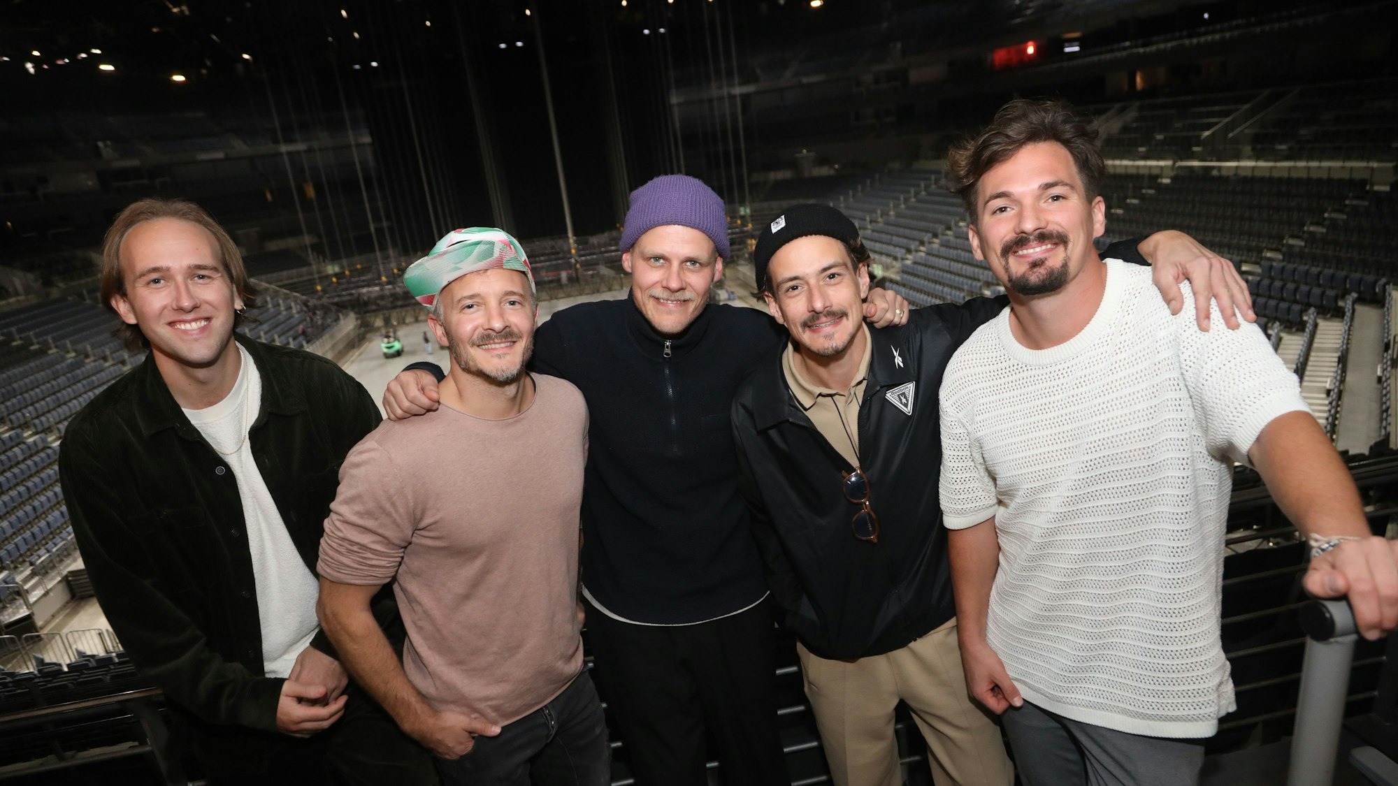 Die Musikband Cat Ballou vor den Rängen der Lanxess-Arena, die Mitglieder schauen glücklich in die Kamera.