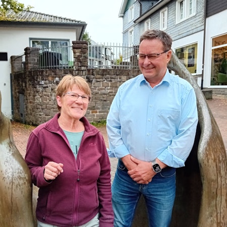 Eine Frau und ein Mann an zwei Bronze-Figuren.