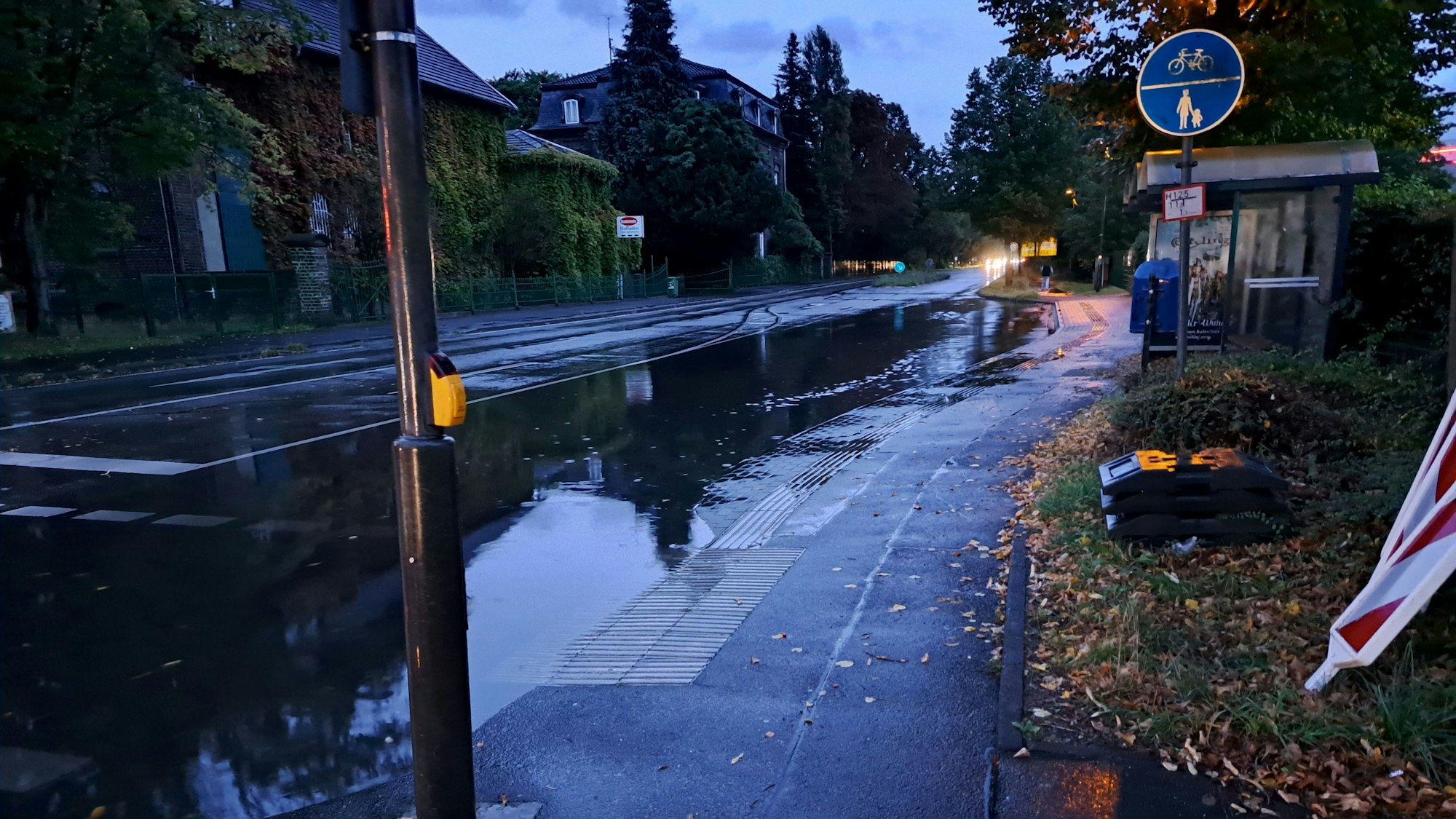 Eine vollgelaufene Straße vor einer Bushaltestelle.