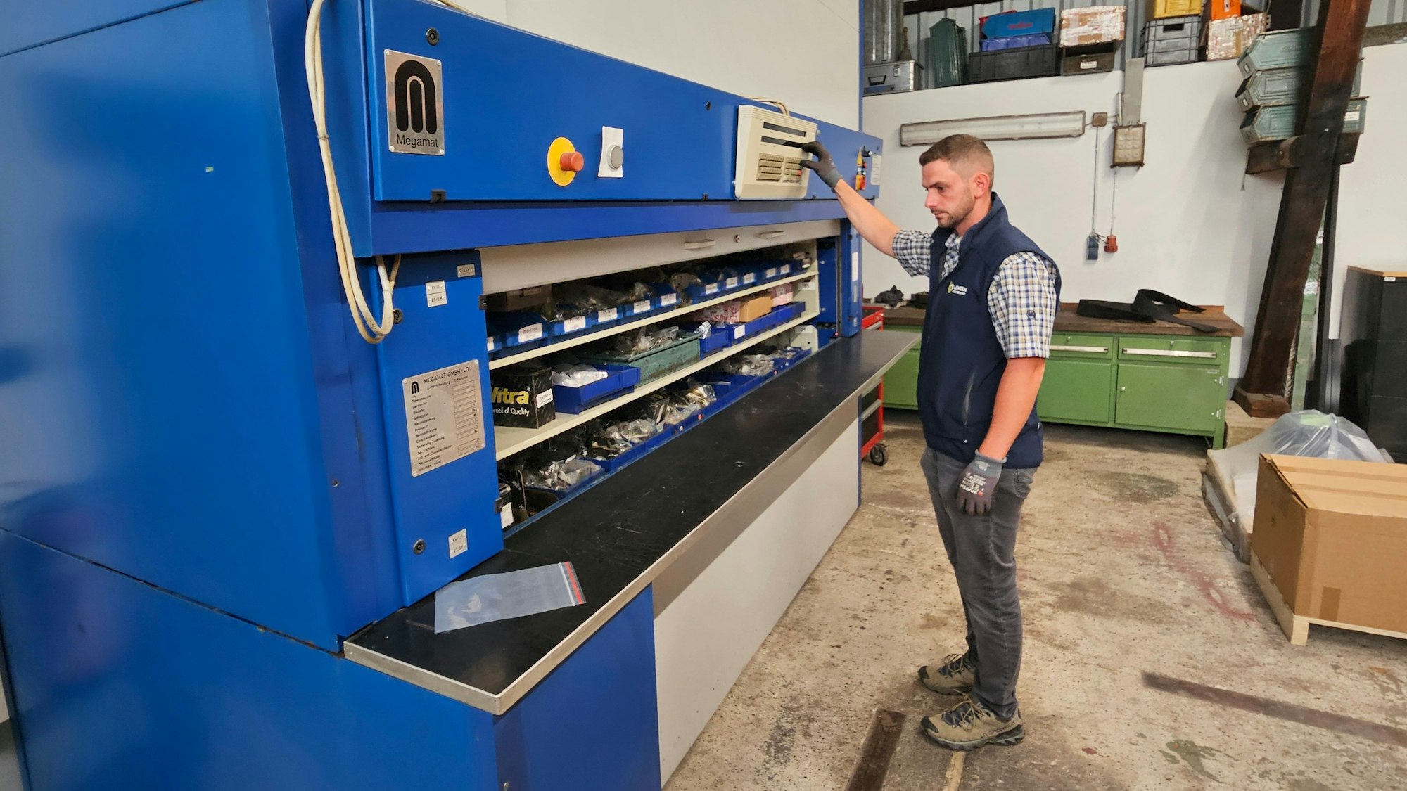 Christoph Wiesen steht vor einem Umlaufregal und drückt auf eine Taste.