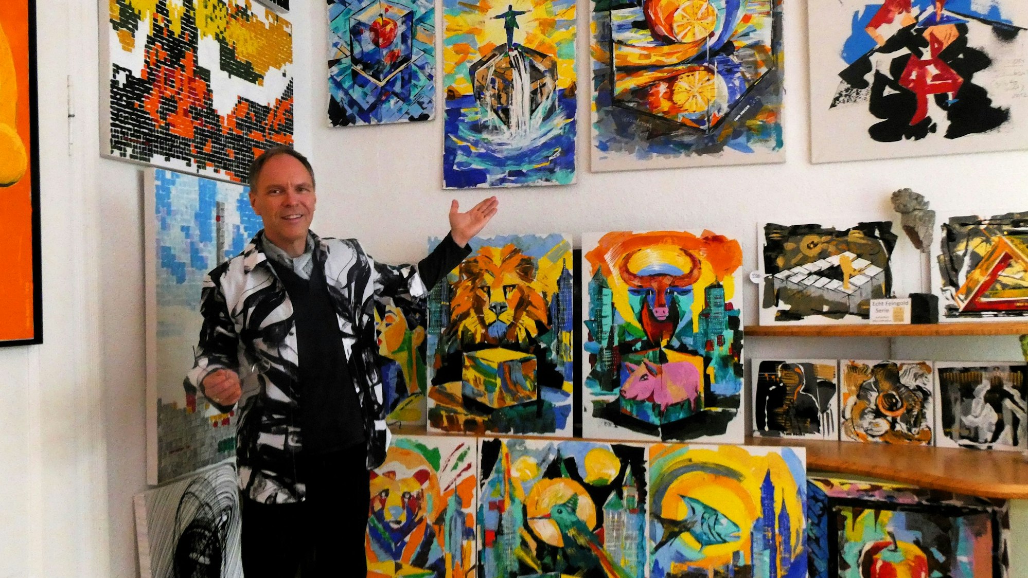 Ein Mann vor einer Wand voller sehr bunter Bilder.