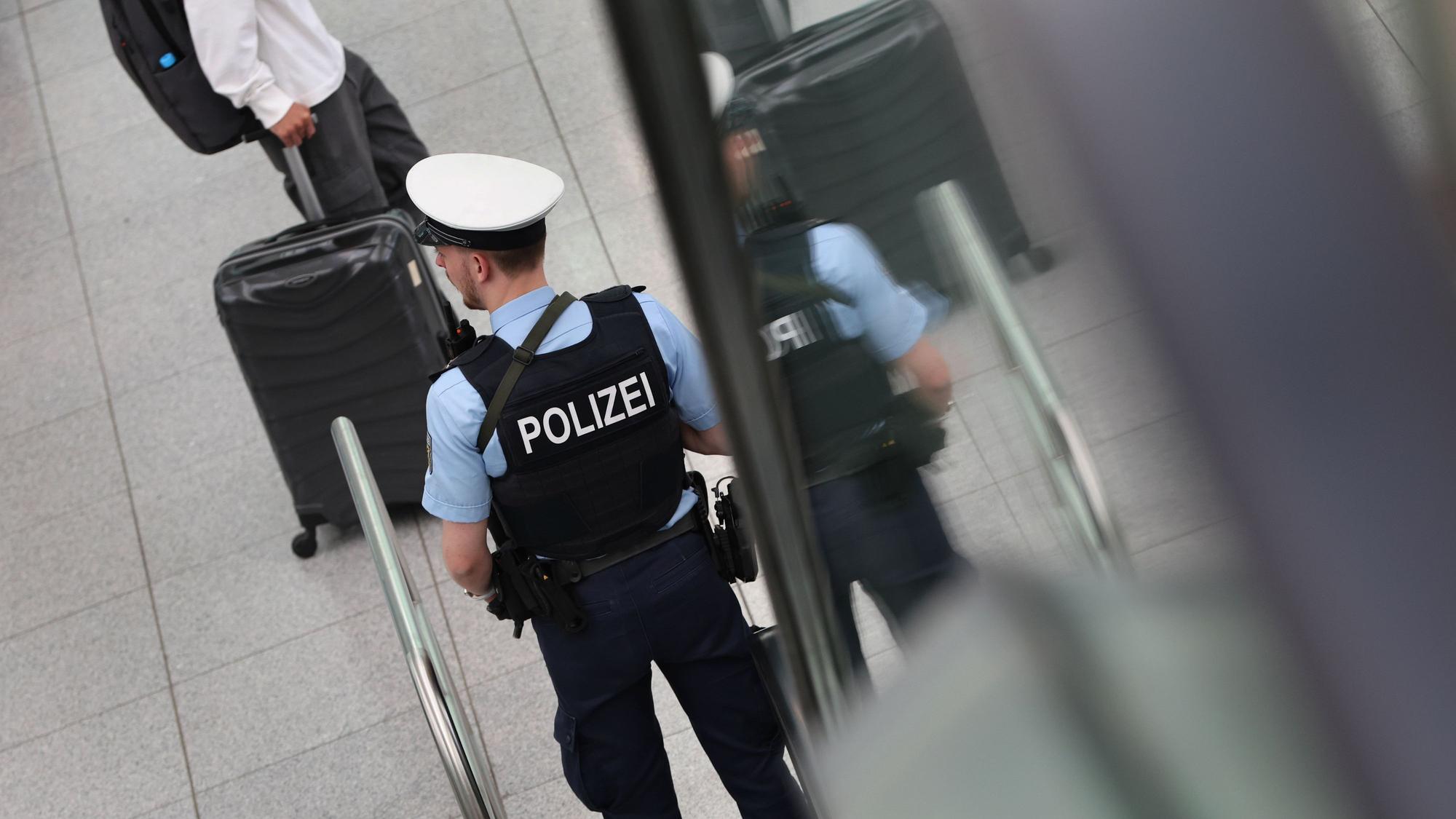 Ein Bundespolizist steht beim Besuch an einer Rolltreppe vor Reisenden. (Symbolbild)