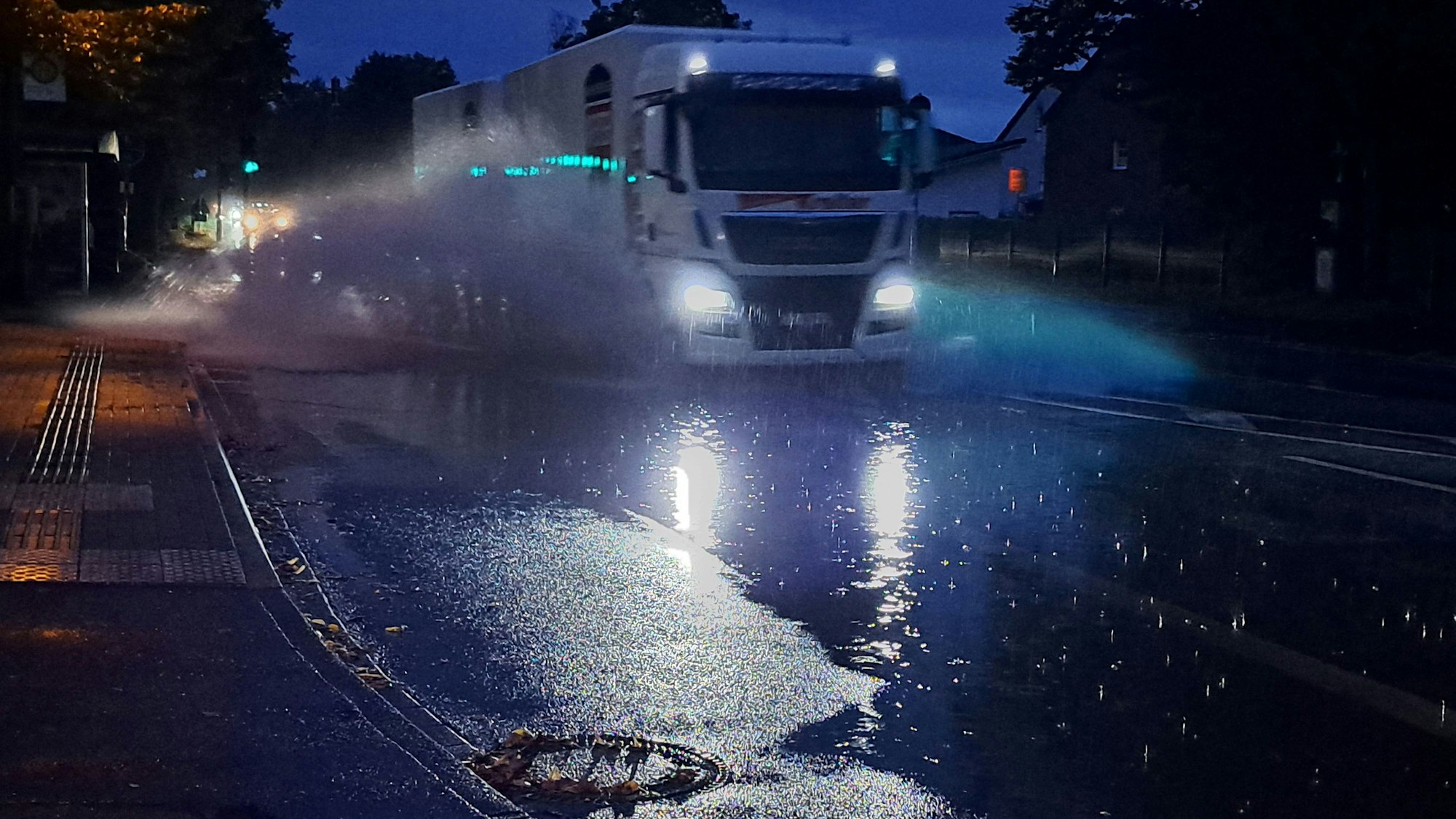 Ein Lkw fährt durch eine große Pfütze und Wasser spritzt hoch.