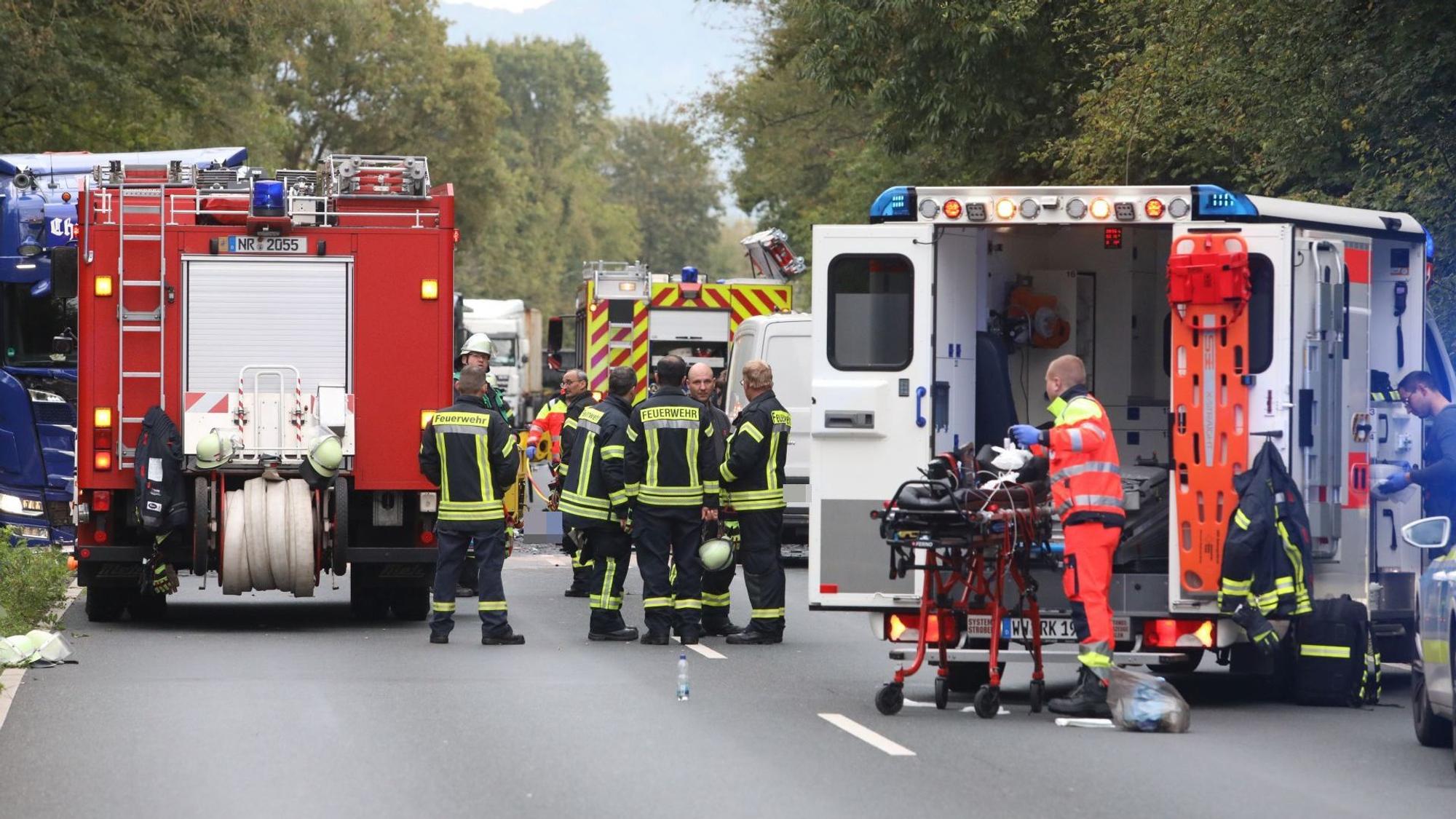 Rettungskräfte von Feuerwehr und Rettungsdienst und ihre Fahrzeuge stehen auf einer Straße.