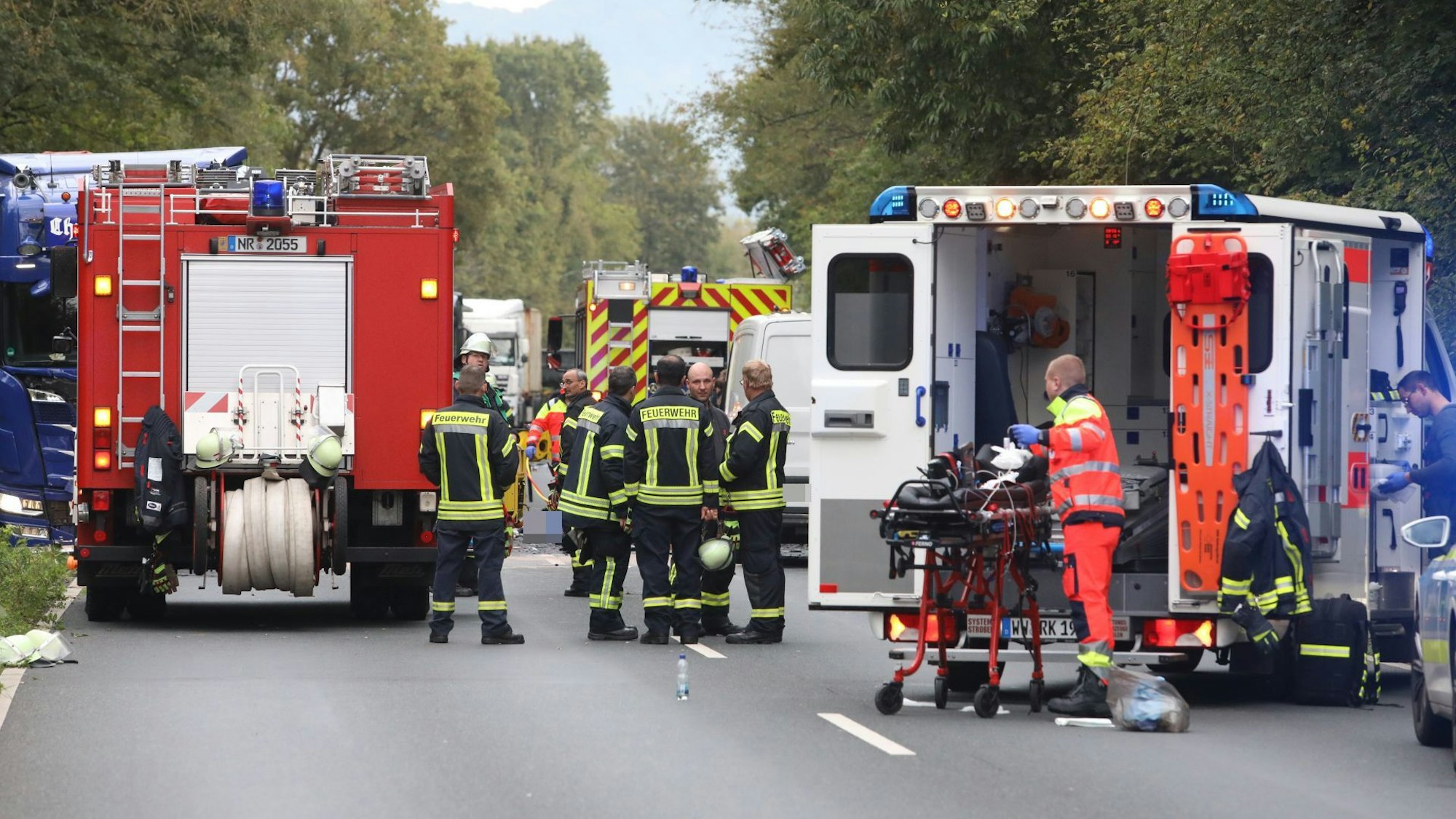 Rettungskräfte von Feuerwehr und Rettungsdienst und ihre Fahrzeuge stehen auf einer Straße.