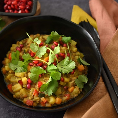 Frische Korianderblätter und Granatapfelkerne sind als Topping über den Linseneintopf gestreut.