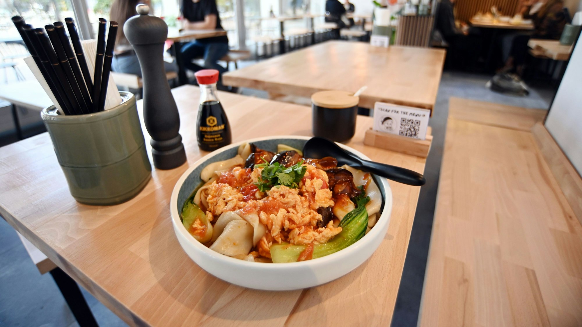 Ein Teller mit einem chinesischen Nudelgericht auf einem Tisch im Restaurant Nai Nai Bao.