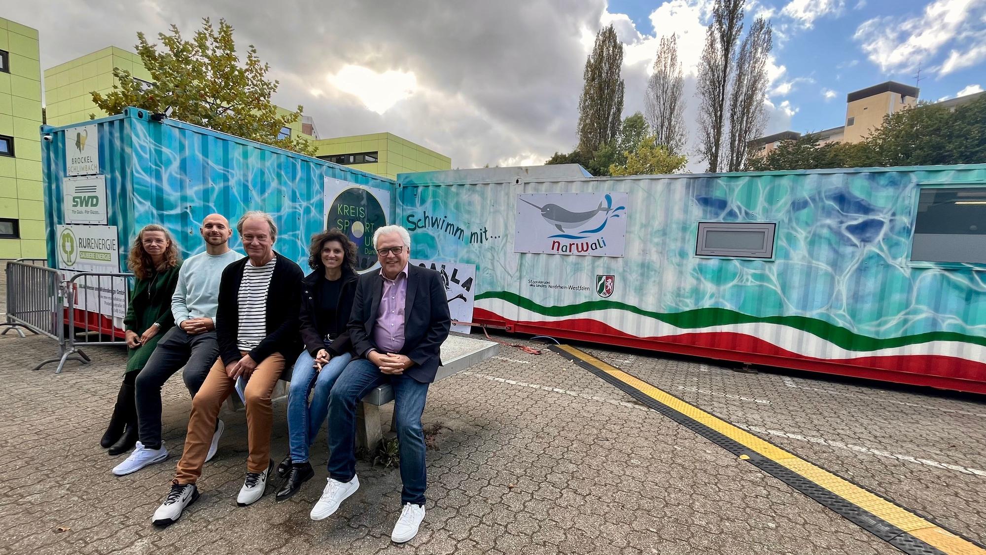 Fünf Menschen vor Schwimmcontainer