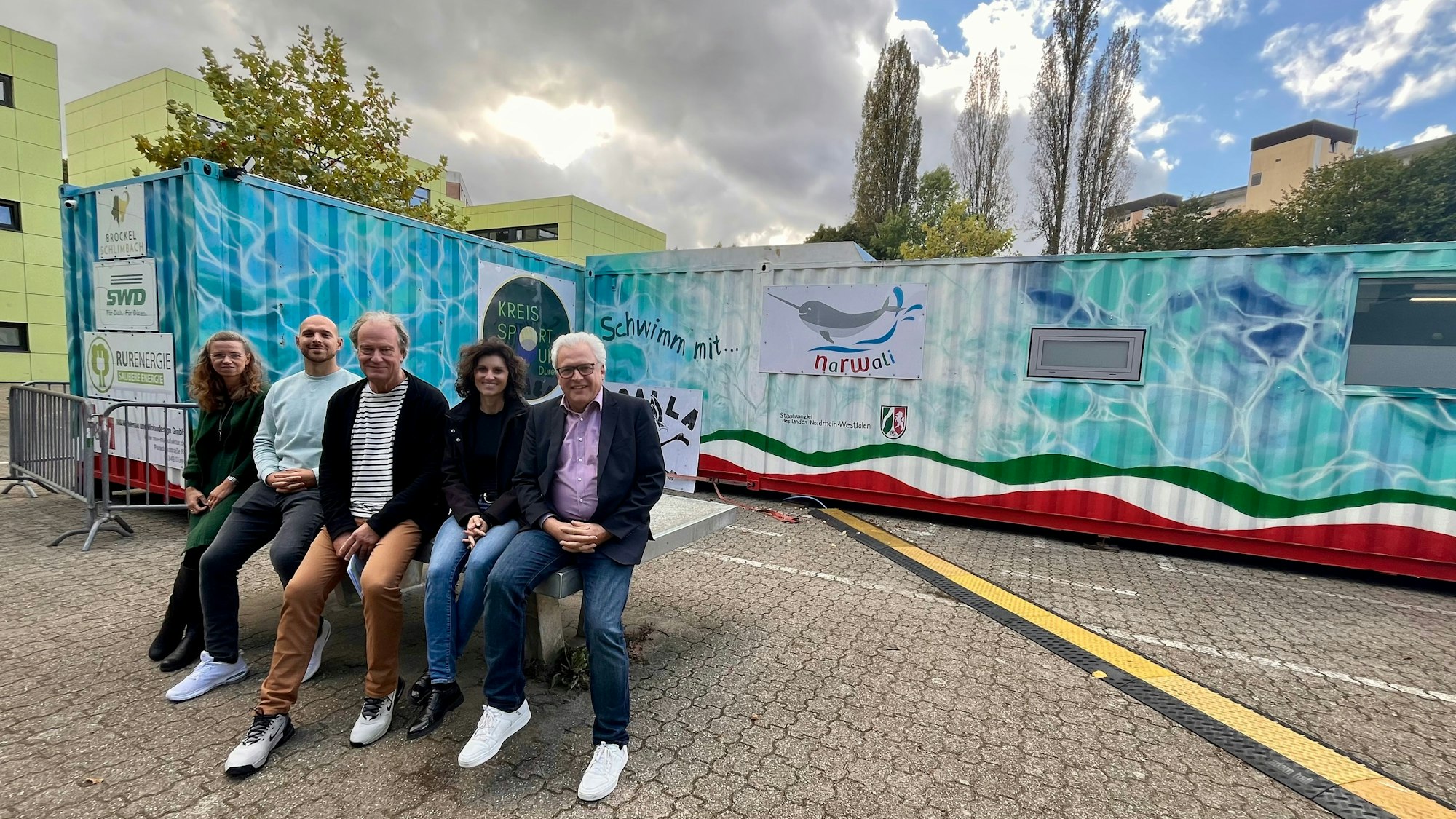 Fünf Menschen vor Schwimmcontainer