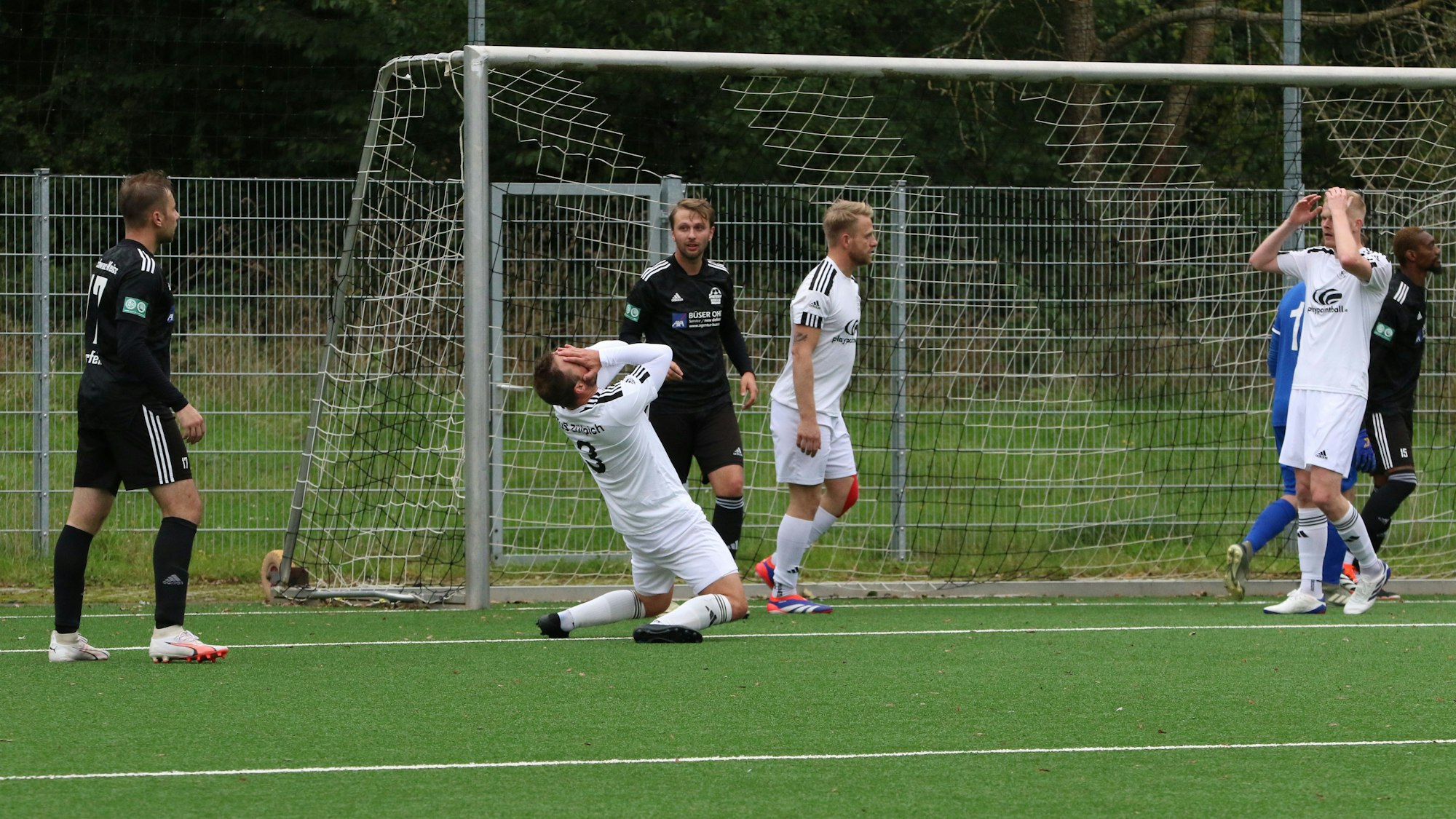 Alexander Ems (2.v.l.) im weißen Trikot des TuS Zülpich und ein Teamkollege schlagen nach einer vergebenen Kopfballchance die Hände vors Gesicht.