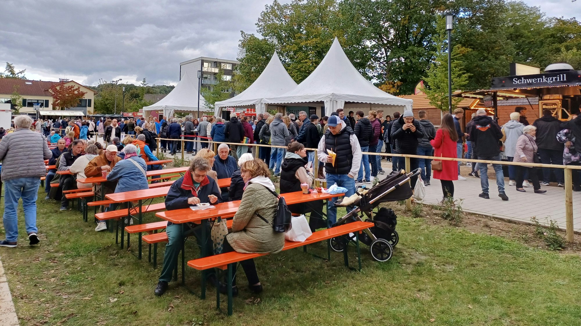 Menschen sitzen an Biertischen auf dem Obstmarkt in Leichlingen.