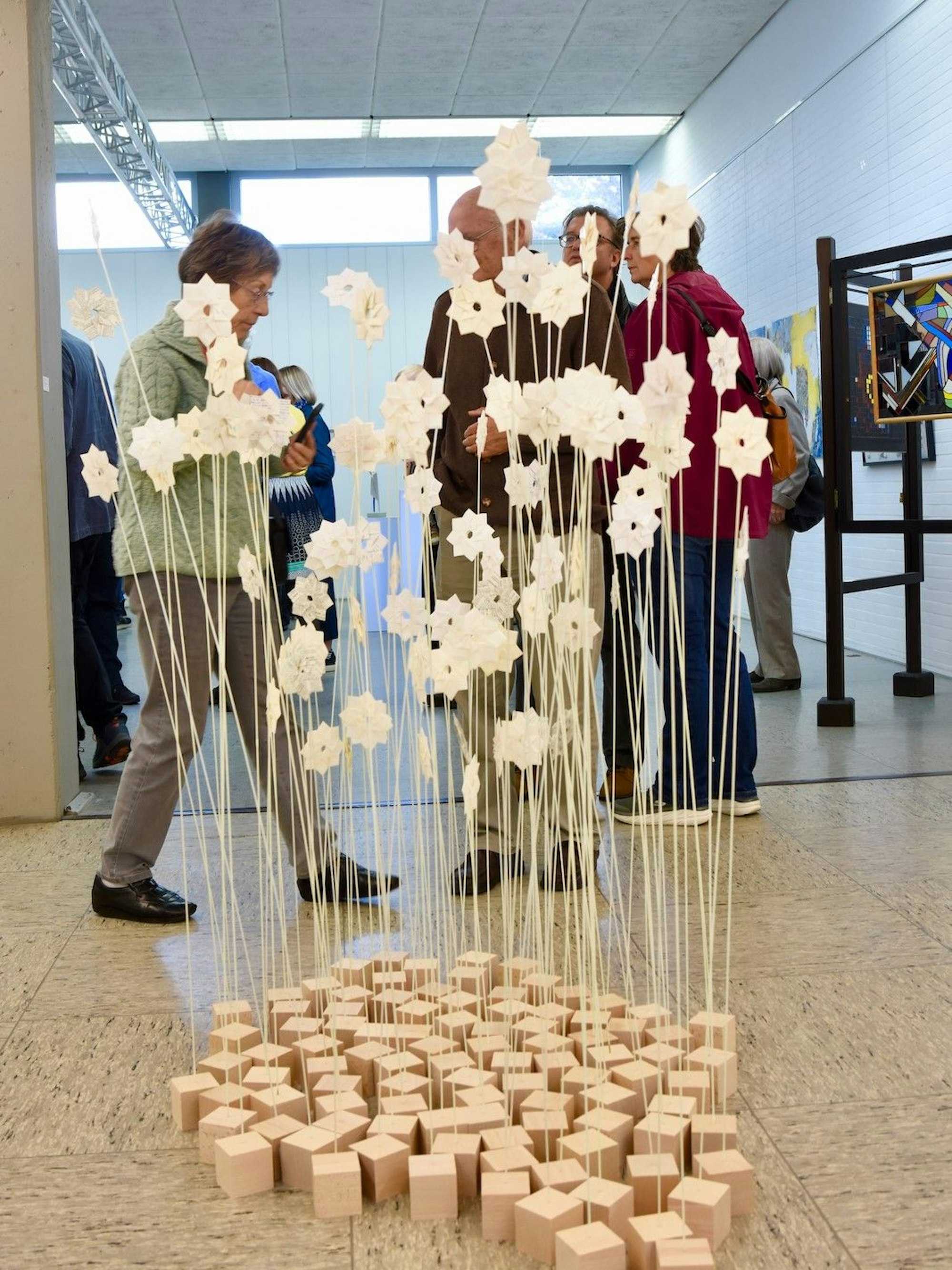 98, an langen Eisenstäben befestigte Papierblumen in Holzsockeln bilden die „Pusteblumen“.