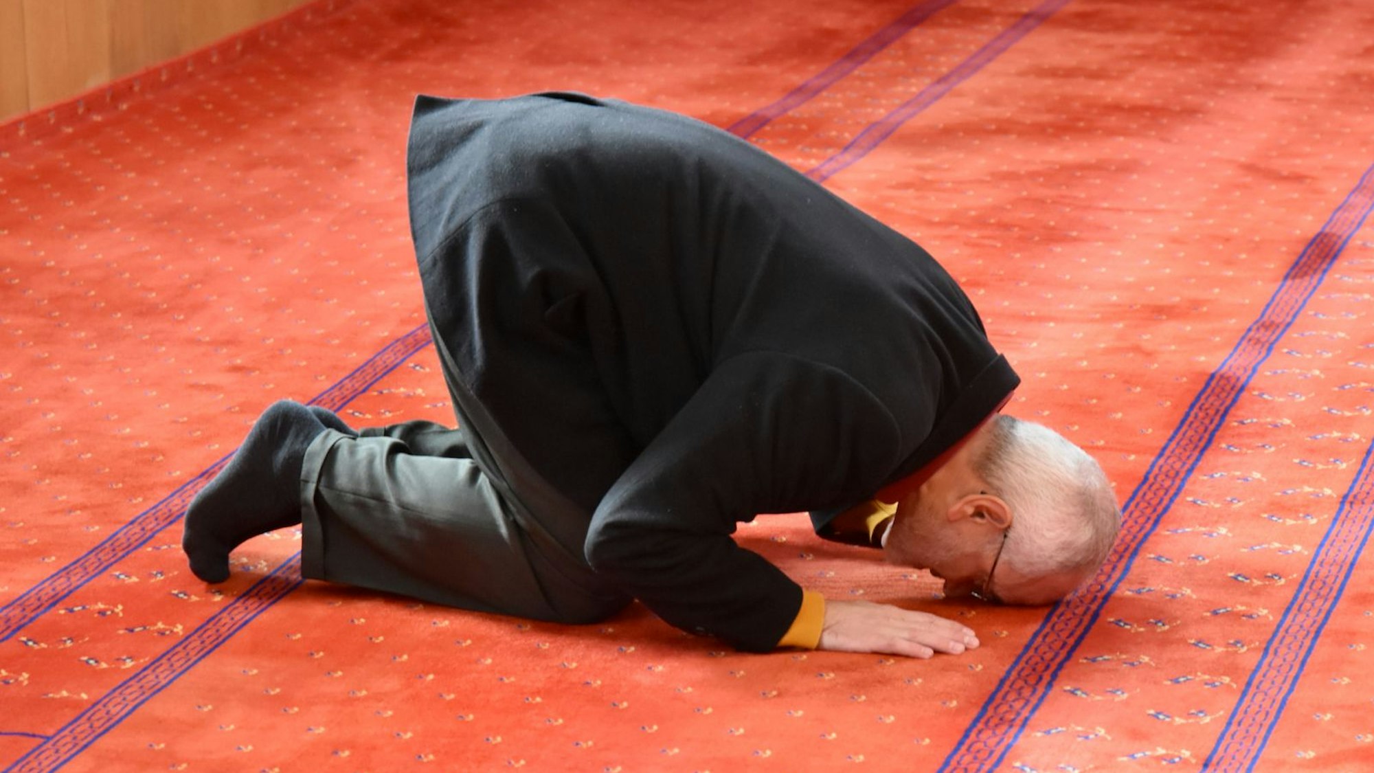 Ein Mann kniet und verbeugt sich zum Gebet gen Mekka.