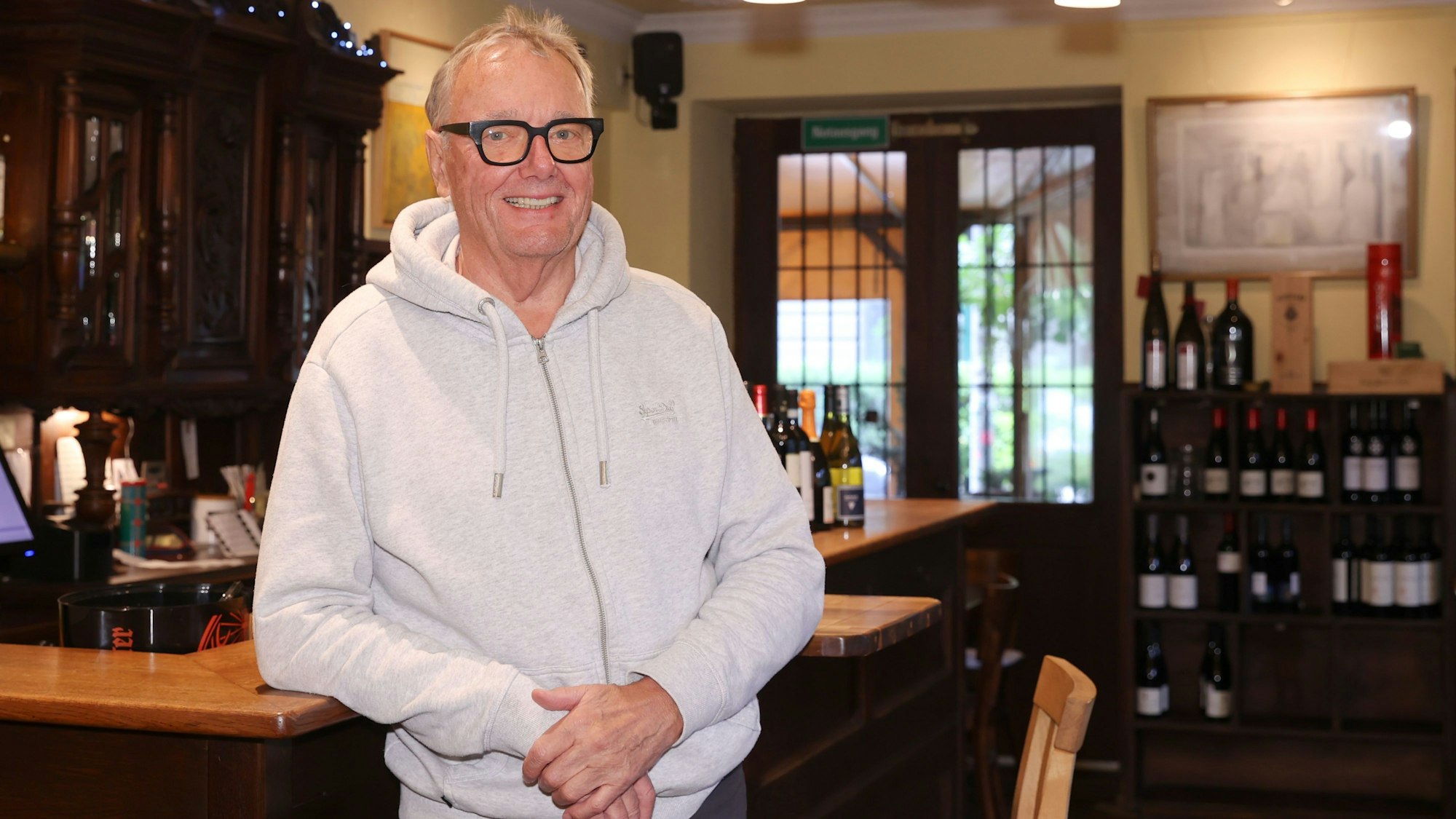 Heiner Welchering steht lächelnd an der Theke in seiner Weinstube.