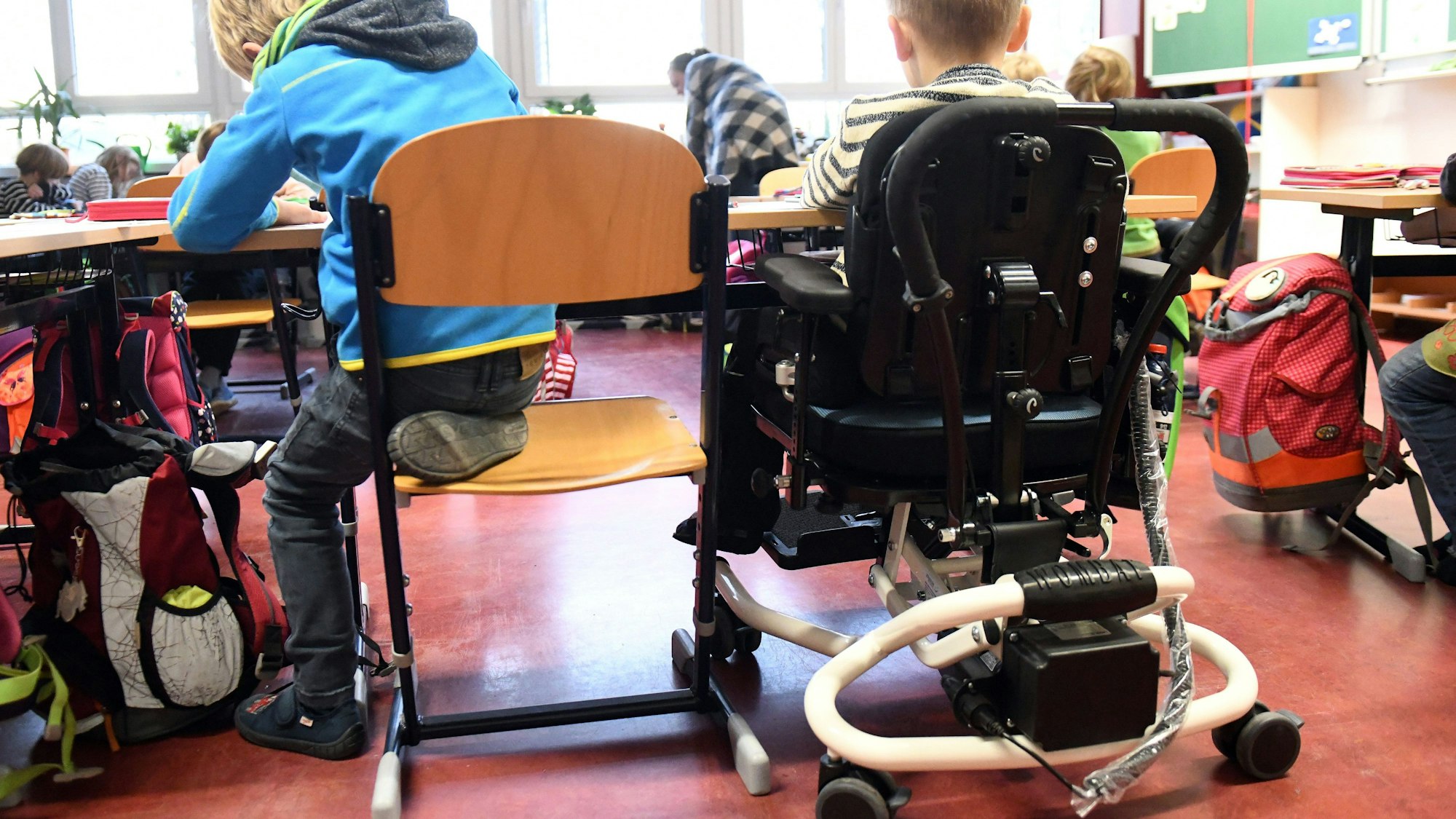 Ein Kind mit Behinderung sitzt in seinem Rollstuhl gemeinsam mit anderen Erstklässlern ohne Handicap in einem Klassenraum. Die SPD-Opposition sieht in Nordrhein-Westfalen große Defizite auf dem Weg zur gleichberechtigten gesellschaftliche Teilhabe von Menschen mit Behinderung.
