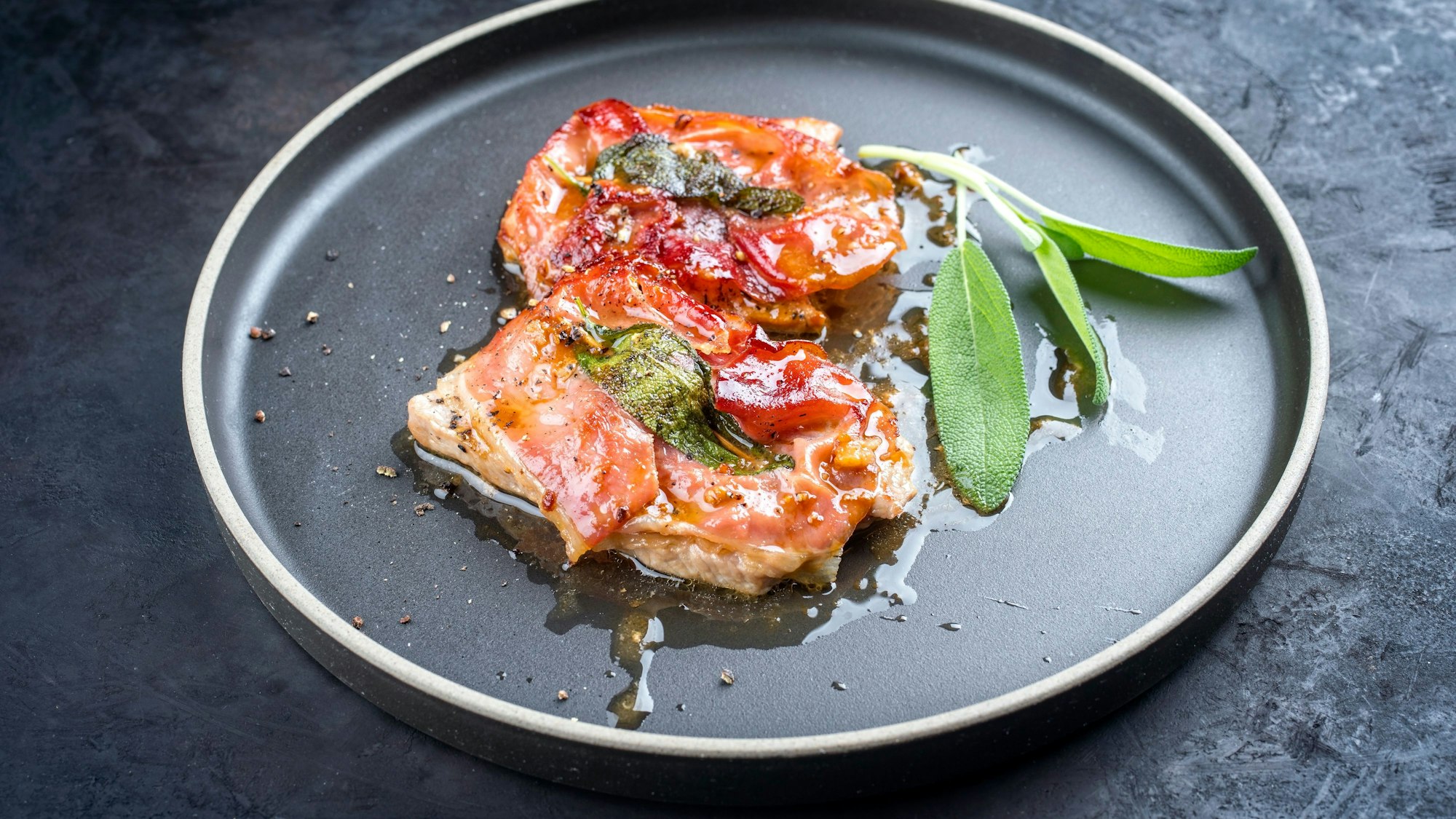 Modern style traditional Italian fried pork saltimbocca alla Romana with Parma ham and sage leaves offered as close-up in a Nordic design plate xkwx Saltimbocca, schnitzel, veal, escalope, pork, topside, Parma, ham, gammon, turkey escalope, steak, chicken, mangalica, Italian, scallop, cuisine, garlic, fried, sauce, meat, herb, sage, food, recipe, meal, pepper, spice, crust, board, gourmet, offer, plate, modern, style, design, Nordic, brown, black, red, rustic, top view, overhead, close-up, traditional, classic, restaurant, catering, street food, texture