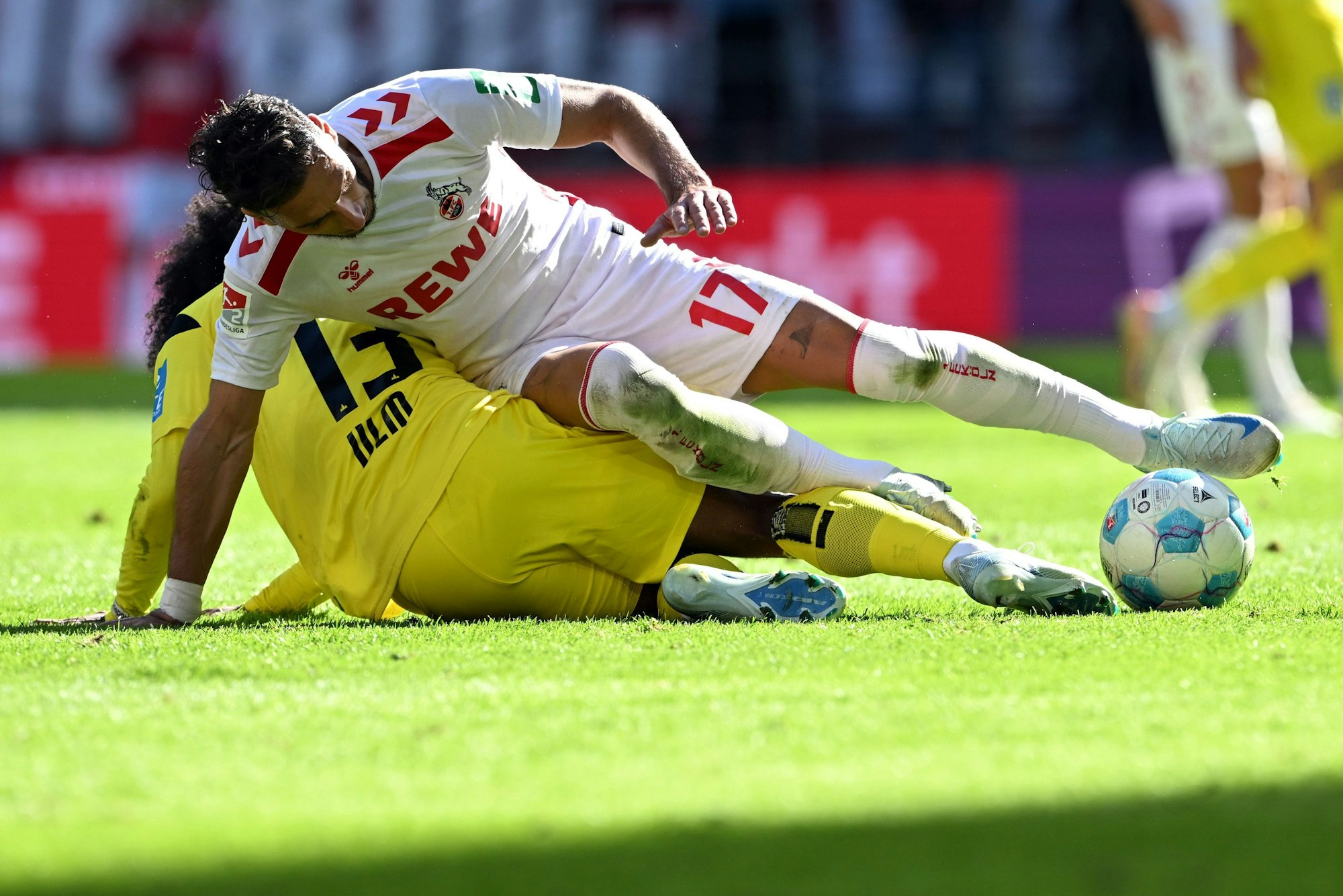 Kölns Leart Paqarada und Ulms Jayden Nelson (u,) kämpfen um den Ball.
