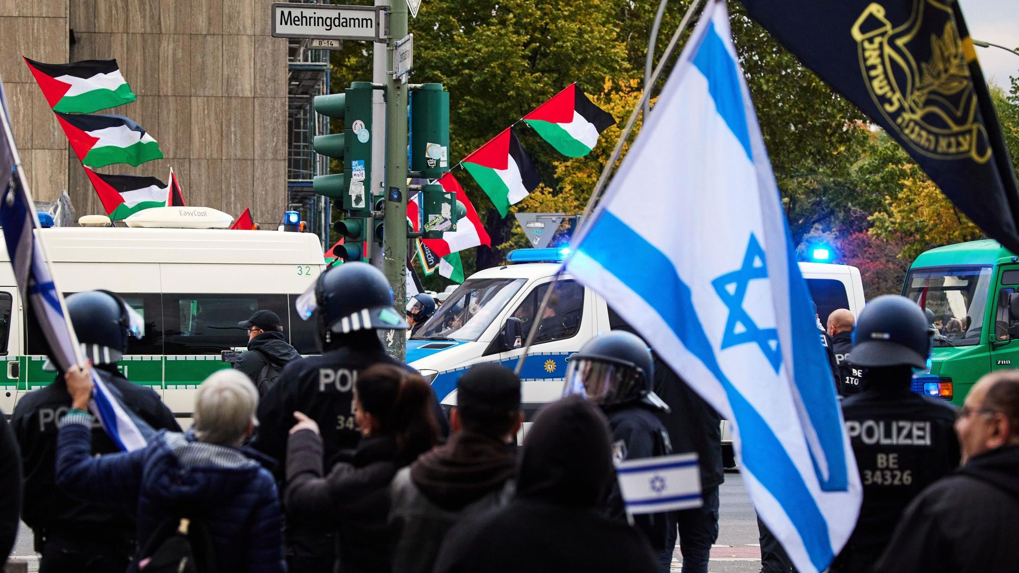 05.10.2024, Berlin: Teilnehmer einer proisraelischen Demonstration (vorne) als Gegenveranstaltung einer propalästinensischen Demonstration anlässlich des ersten Jahrestages des Überfalls der Hamas auf Israel halten an der Ecke Mehringdamm/Blücherstraße israelische Flaggen. Foto: Joerg Carstensen/dpa +++ dpa-Bildfunk +++