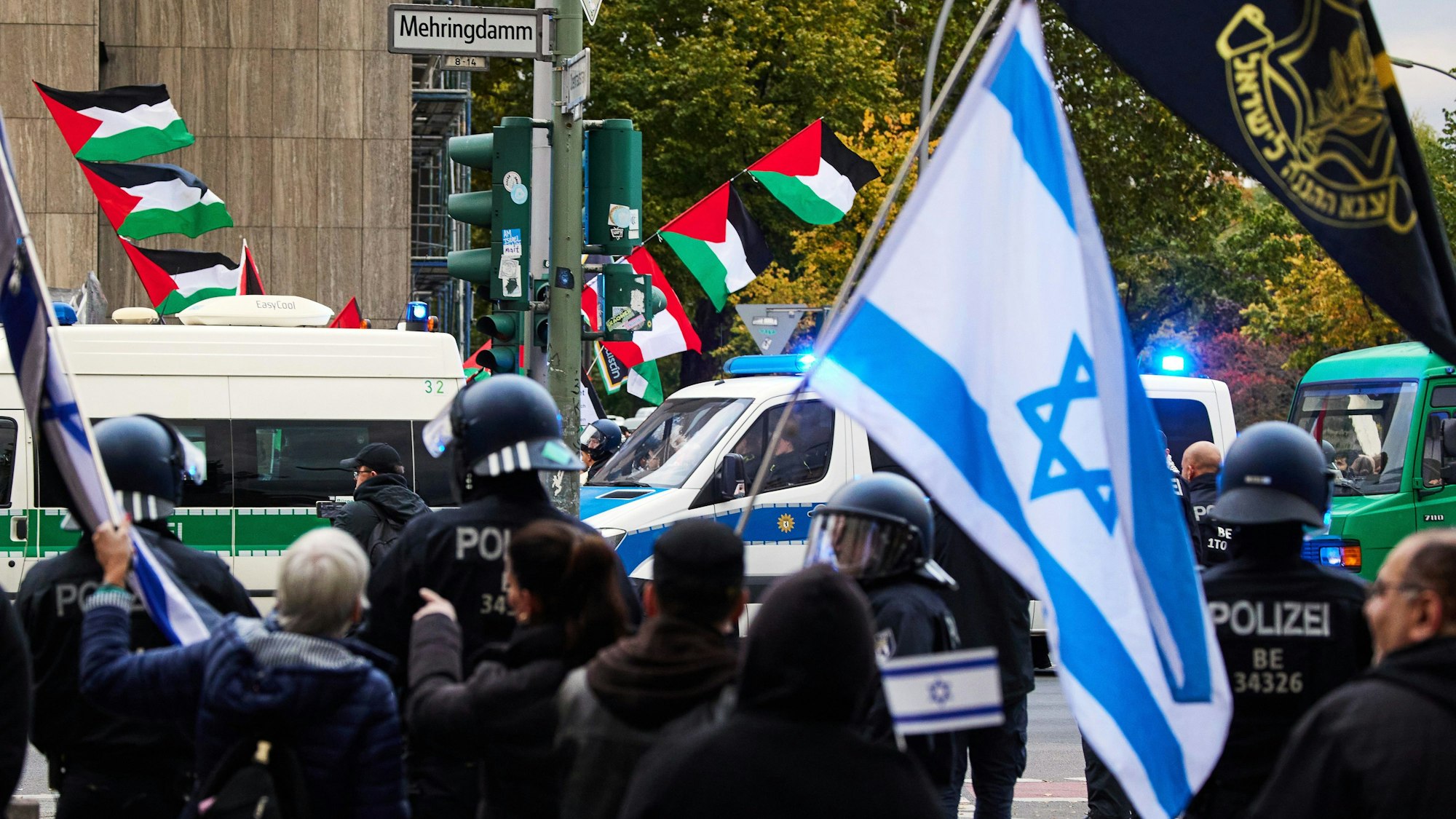 05.10.2024, Berlin: Teilnehmer einer proisraelischen Demonstration (vorne) als Gegenveranstaltung einer propalästinensischen Demonstration anlässlich des ersten Jahrestages des Überfalls der Hamas auf Israel halten an der Ecke Mehringdamm/Blücherstraße israelische Flaggen. Foto: Joerg Carstensen/dpa +++ dpa-Bildfunk +++