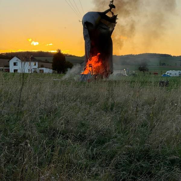 Die Hülle eines Heißluftballons hängt bei Zülpich-Schwerfen in einer Stromleitung. Der Korb darunter brennt.
