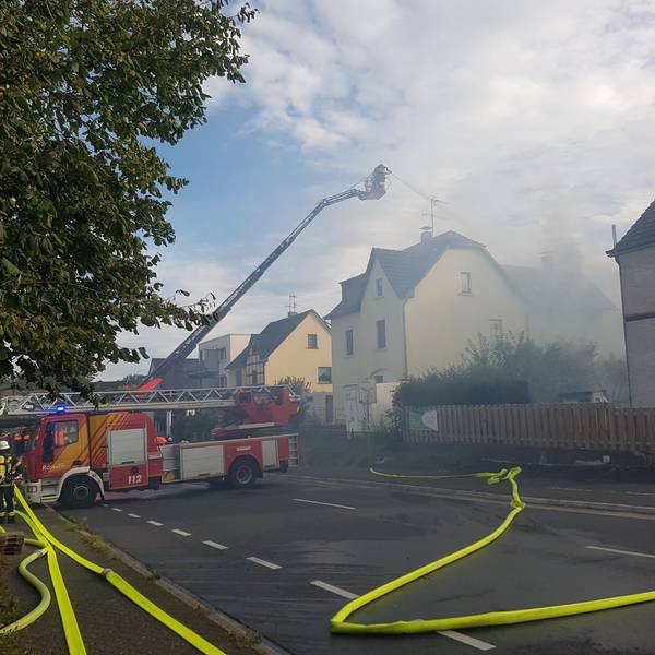 Von einer Drehleiter aus löschen Feuerwehrleute ein brennendes Haus.