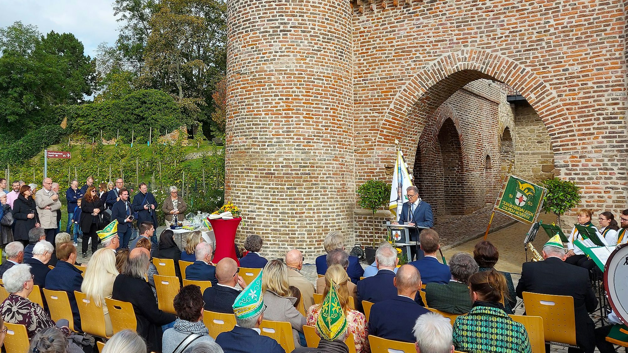Zuhörer sitzen auf Stühlen vor dem Weiertor und lauschen einem Festredner.