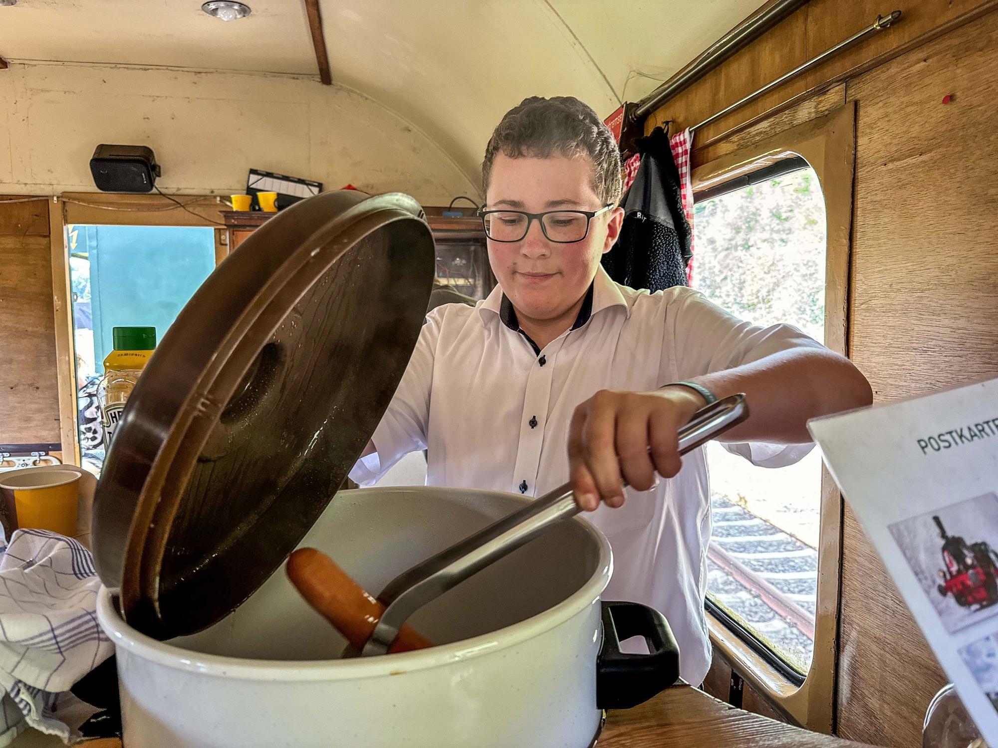 Letzter Fahrtag des Dampfzugs Bergischer Löwe in Oberberg. Die Lkomotive Waldbröl geht in die Winterpause.
Der 14-jährige Marelon Zupke arbeitet im Buffetwagen und holt eine Bockwurst aus dem Kessel.