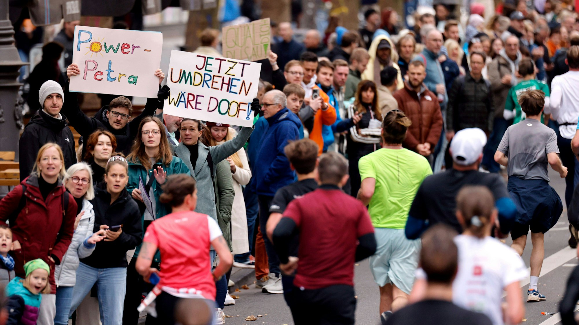 Zuschauer feuern die Läufer mit selbstgebastelten Plakaten an.